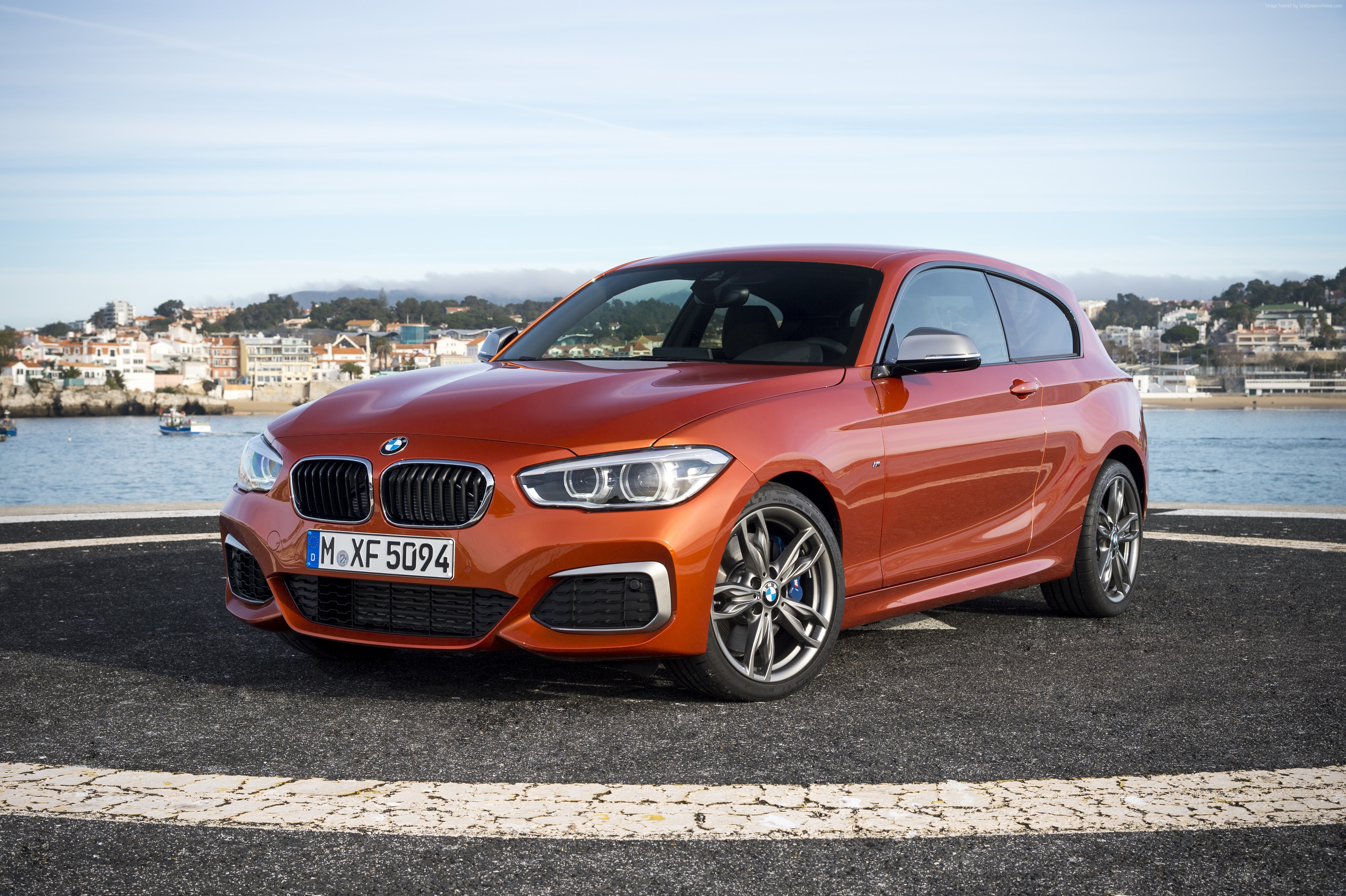Orange BMW M135 hatchback parked by the water HD Wallpaper