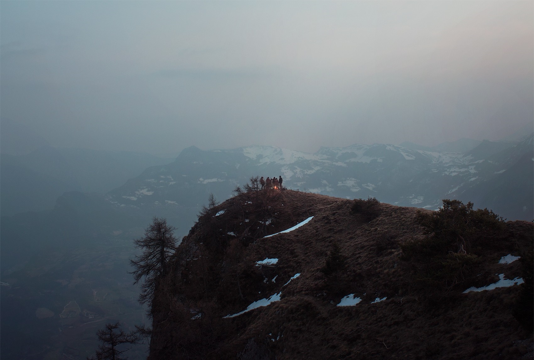 People gathered around a campfire on a mountain ridge at dawn HD Wallpaper