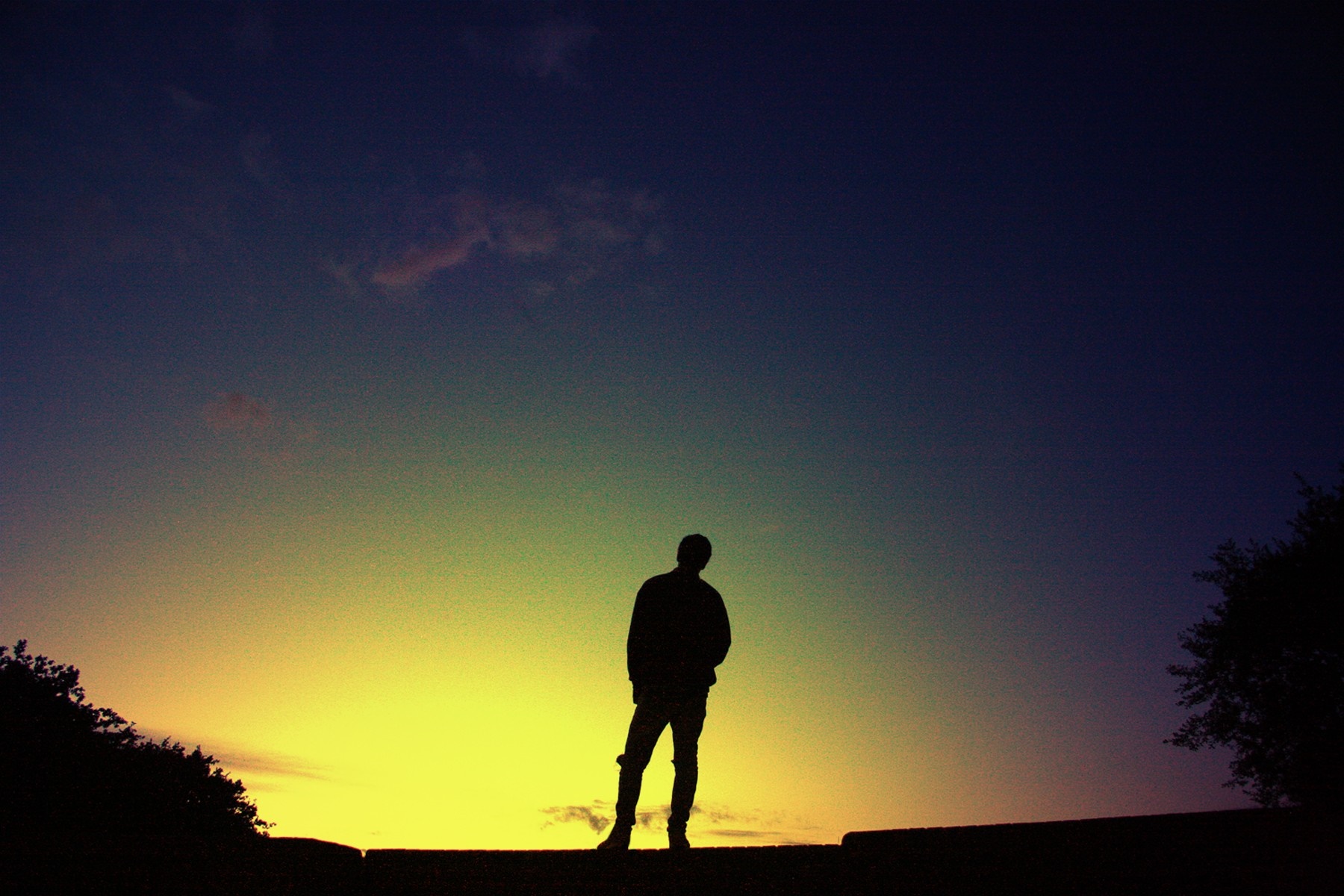 Silhouette of a person against a colorful sunset sky HD Wallpaper