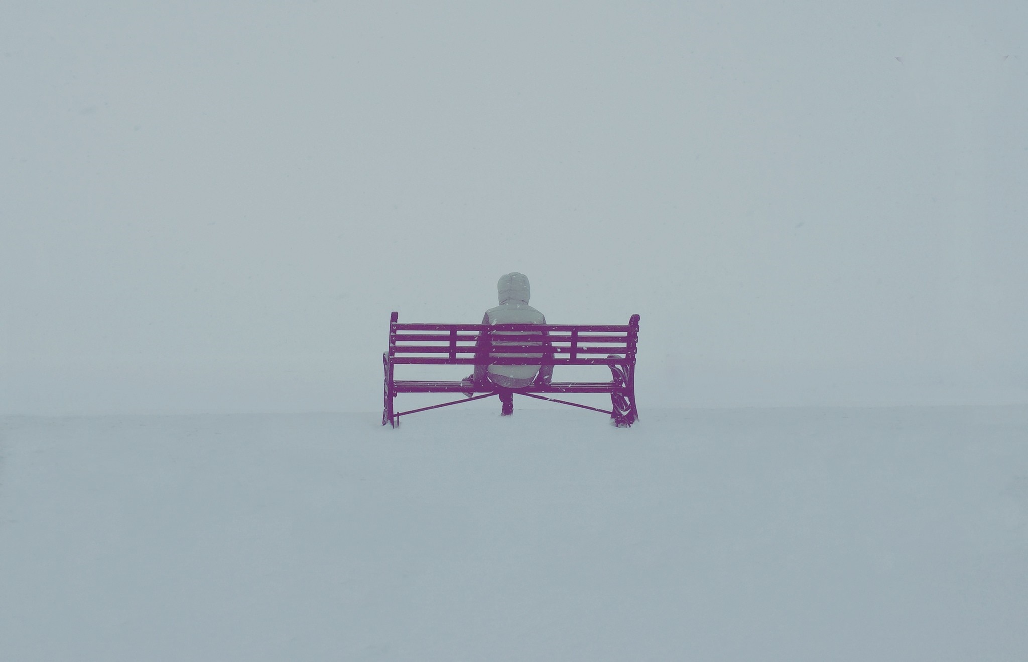 Person sitting on a bench in the snow HD Wallpaper