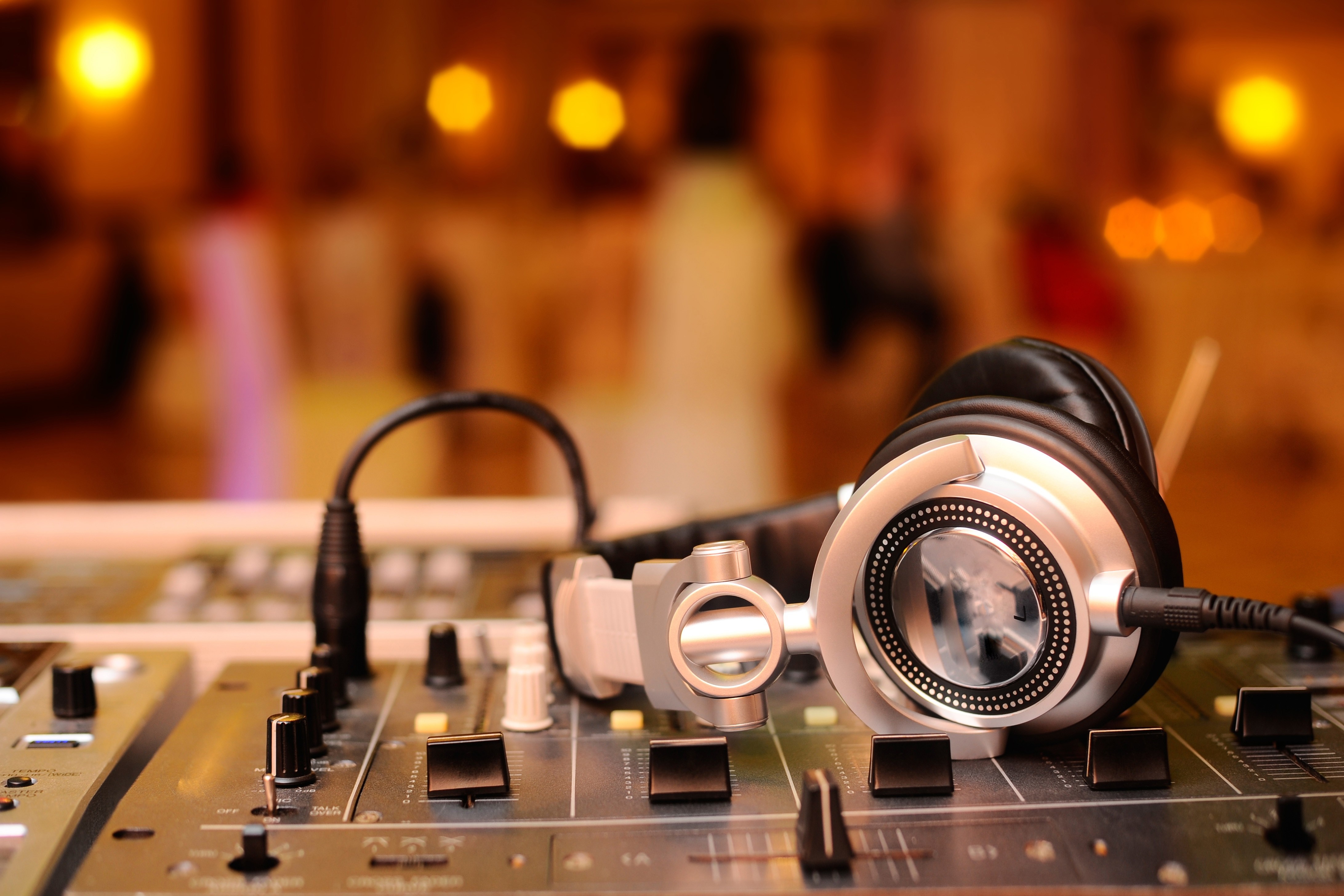 DJ headphones on a mixer with blurred background lights HD Wallpaper