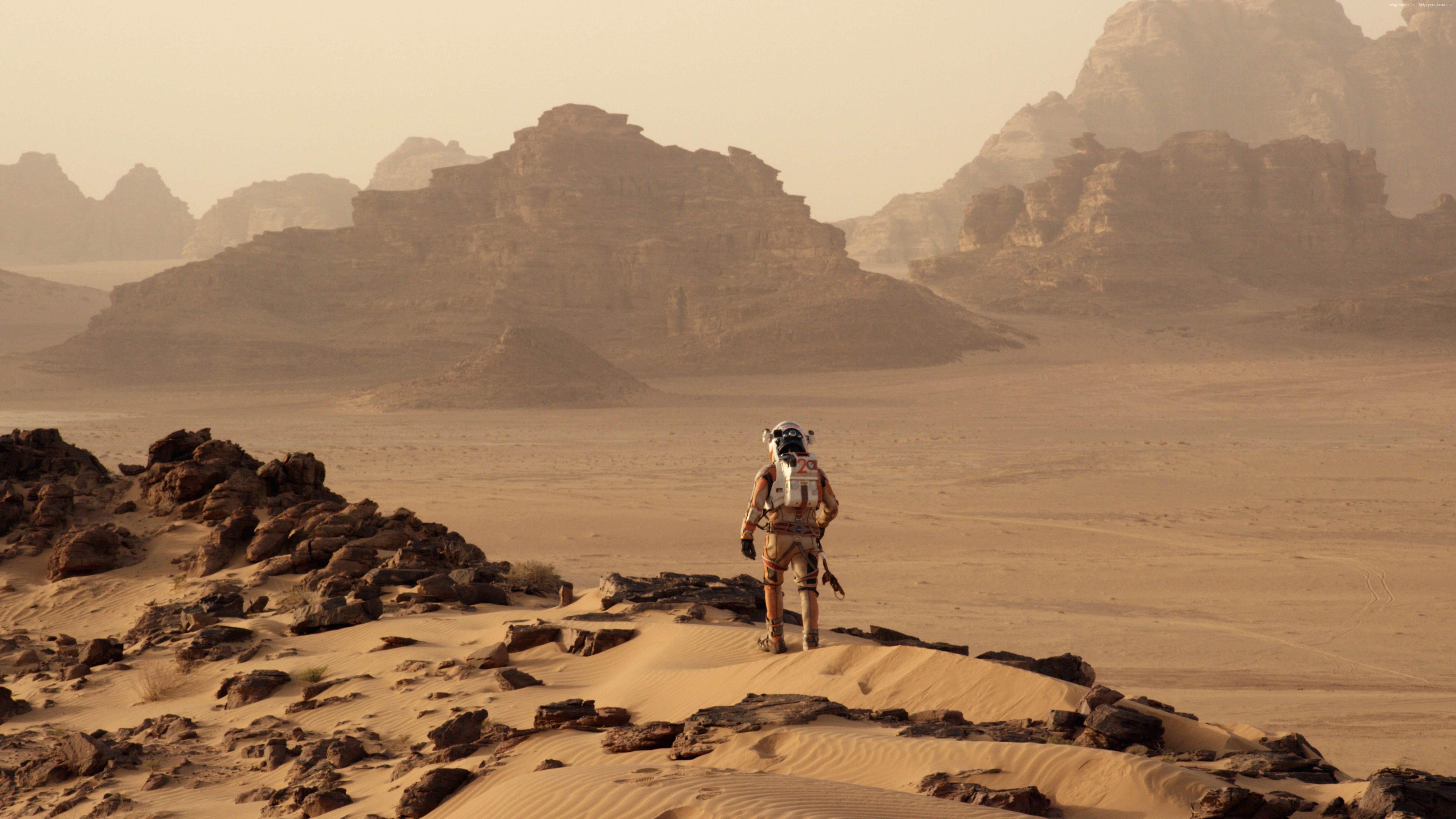 Astronaut on a rocky, sandy planet with mountains HD Wallpaper