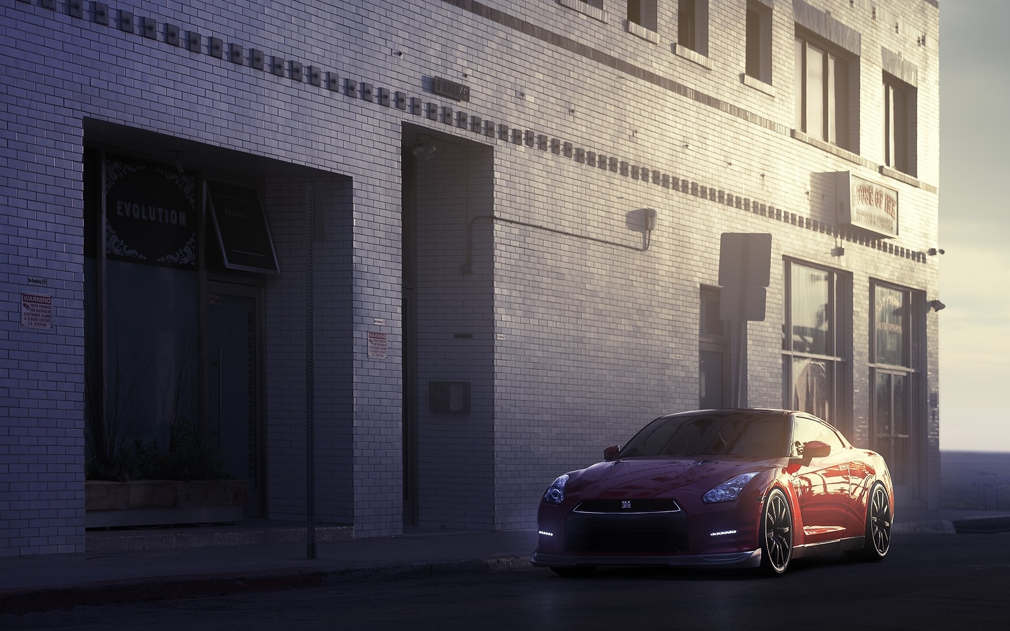 Red Nissan GT-R parked in front of a brick building HD Wallpaper