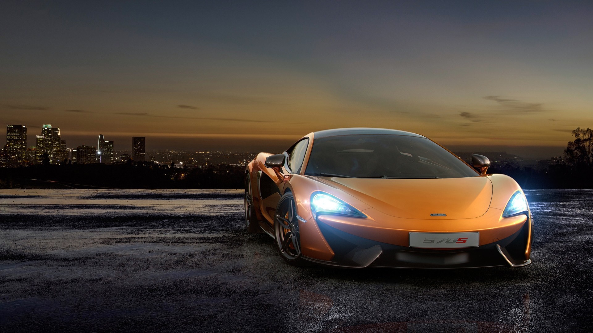 Orange McLaren 570S sports car at dusk with city skyline HD Wallpaper