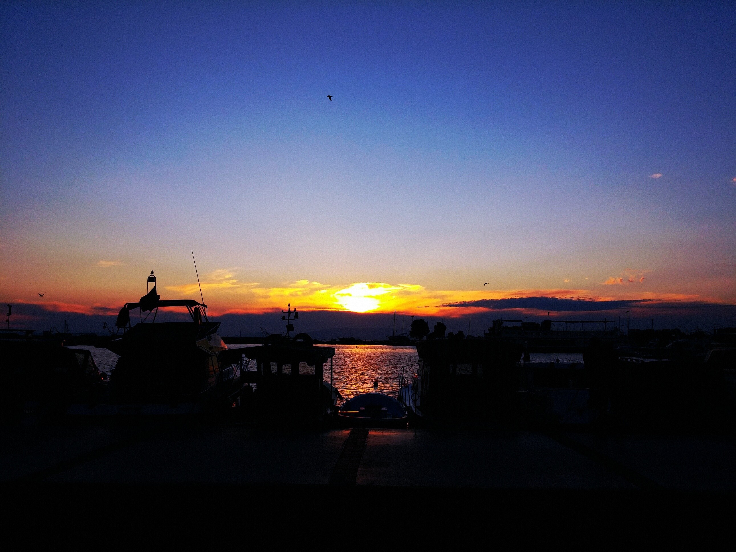 Sunset over the sea with boats in silhouette HD Wallpaper