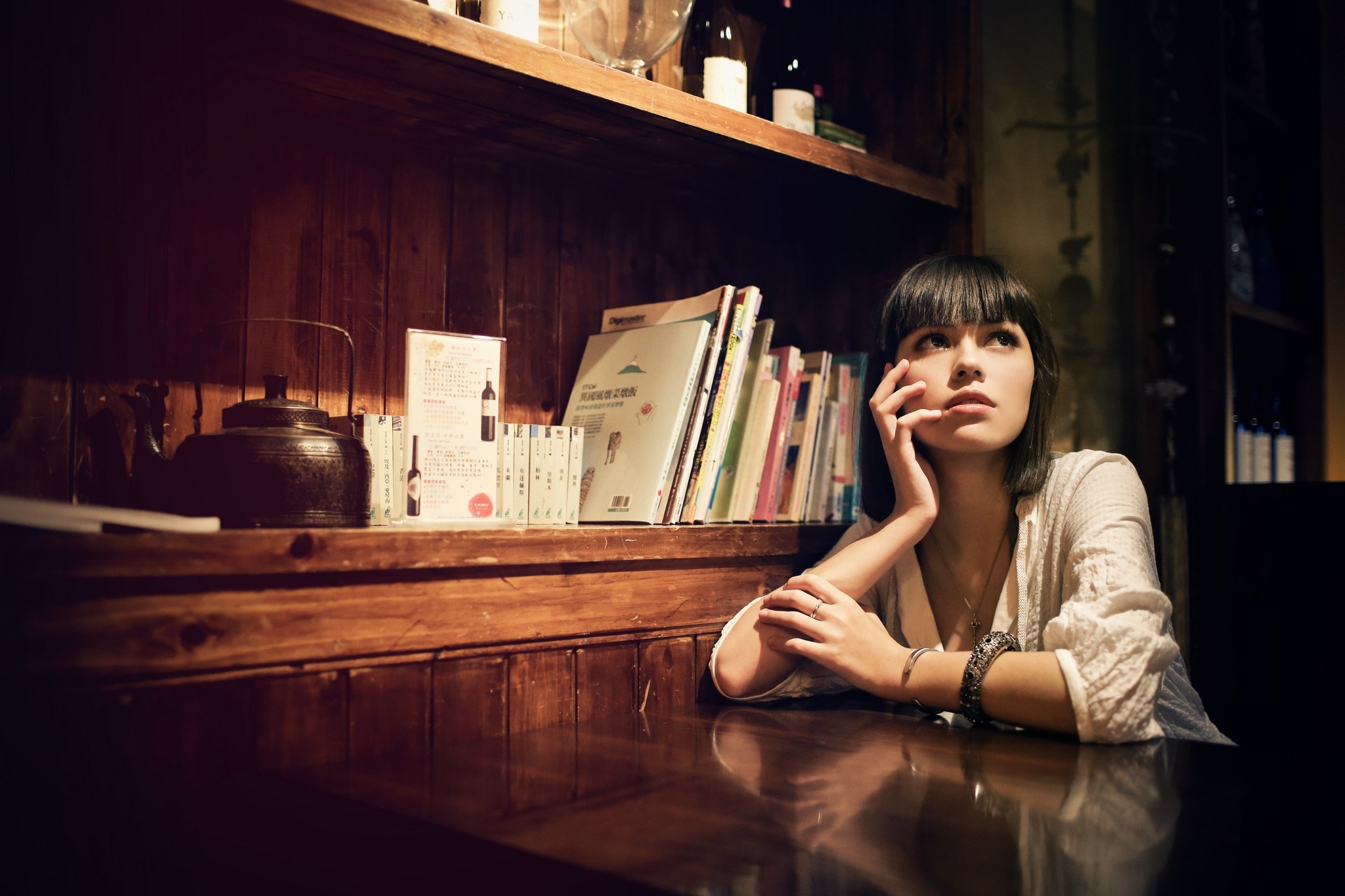 Woman sitting at a table in a dimly lit room HD Wallpaper