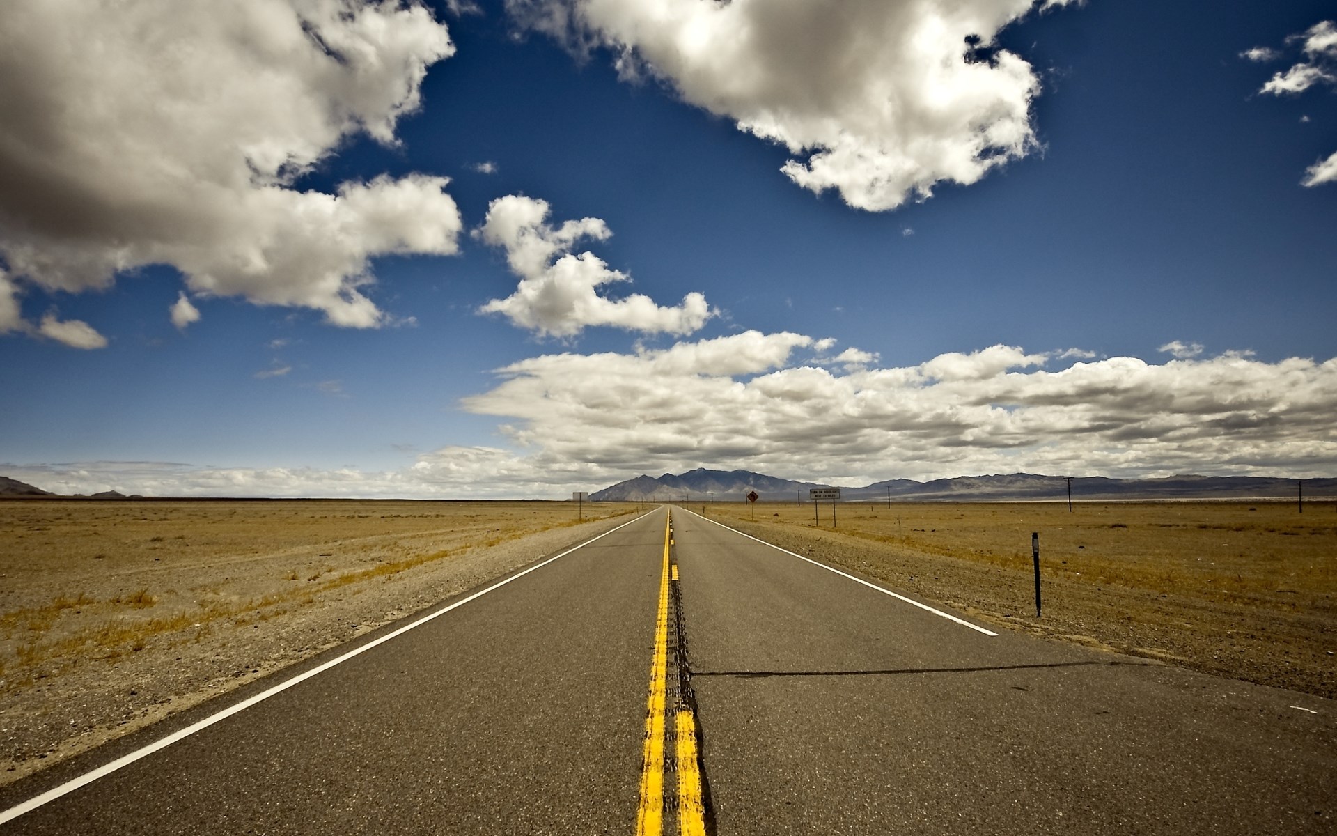 Empty desert highway with mountains in the distance HD Wallpaper