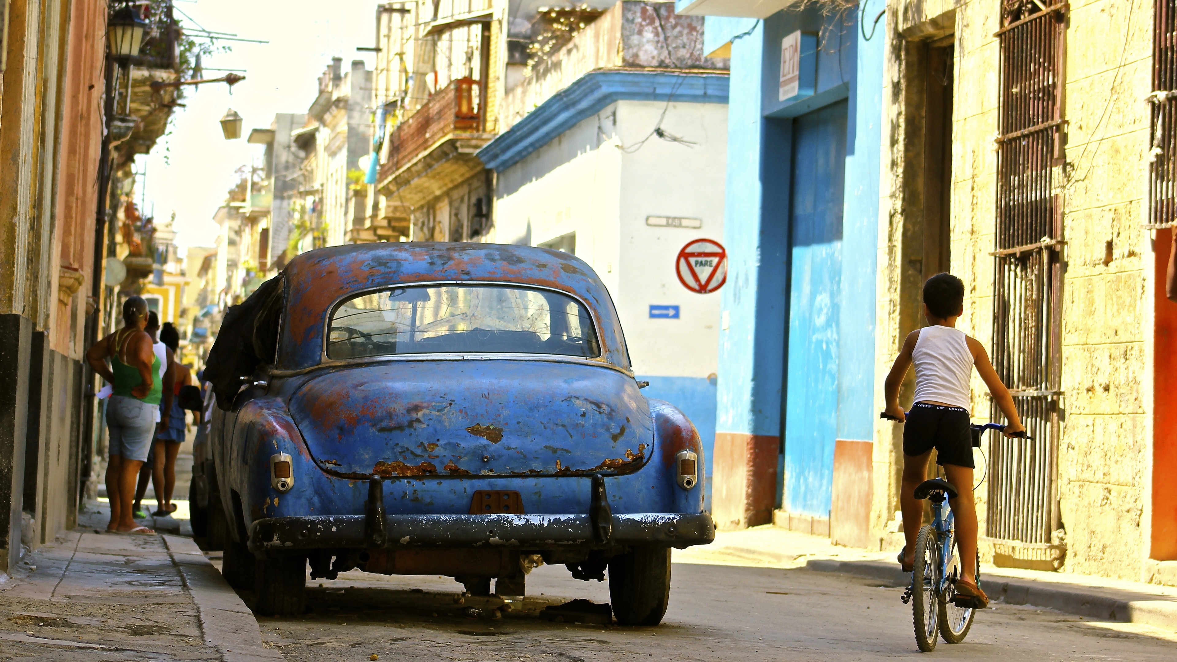 Boy on bicycle near vintage car in Havana, Cuba HD Wallpaper
