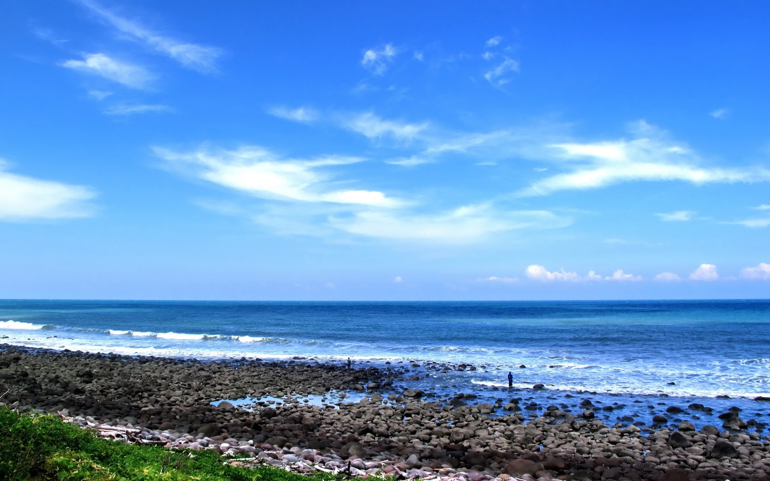 Rocky shore with ocean waves under a blue sky with clouds HD Wallpaper