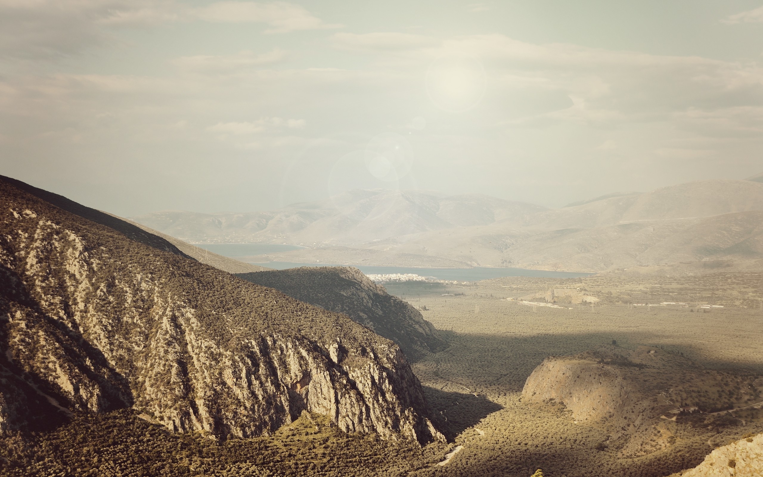 Mountain valley with a distant sea and hazy sky HD Wallpaper
