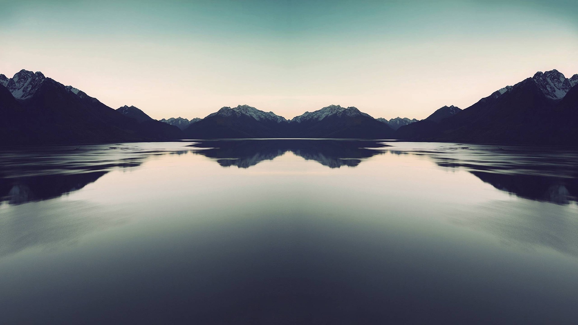 Mirror image of mountains reflecting in a calm lake at dawn HD Wallpaper
