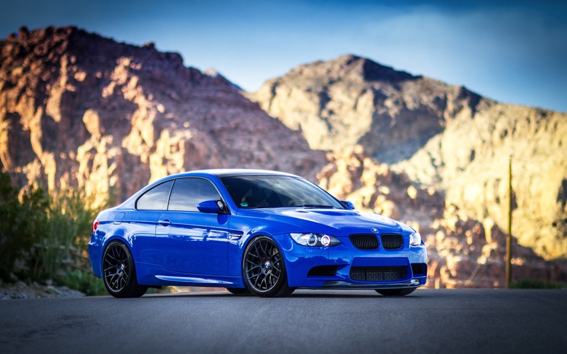 Blue BMW M3 Coupe parked on a road with mountains HD Wallpaper