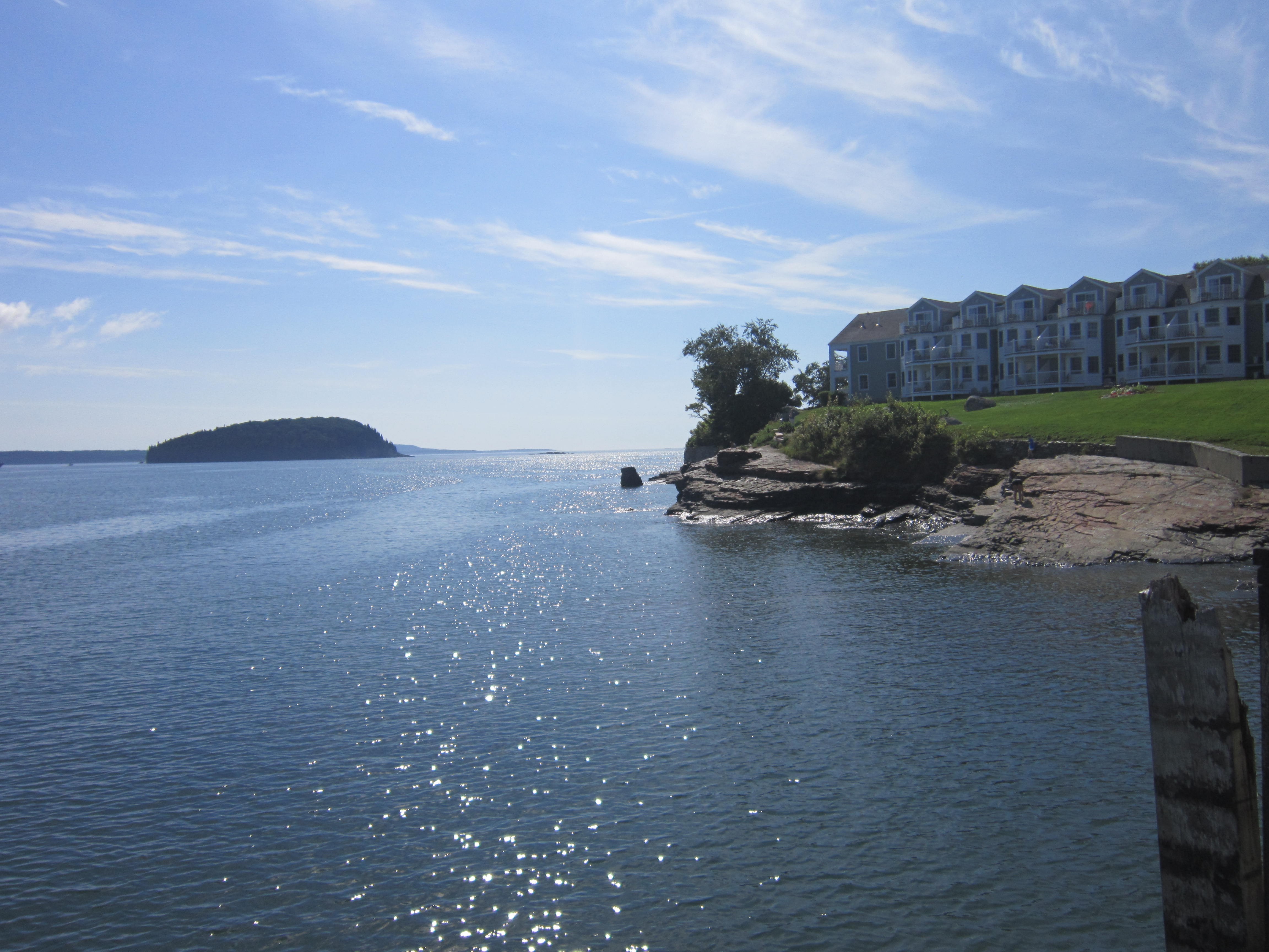 Coastal buildings overlooking a bay with an island in the distance HD Wallpaper