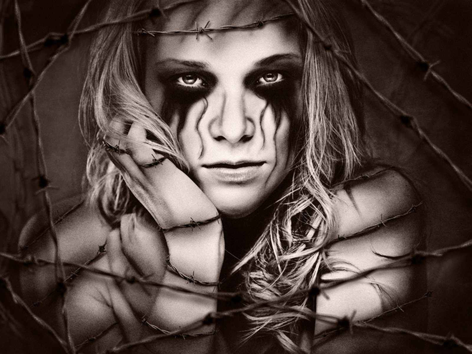 Woman with dark makeup behind barbed wire HD Wallpaper