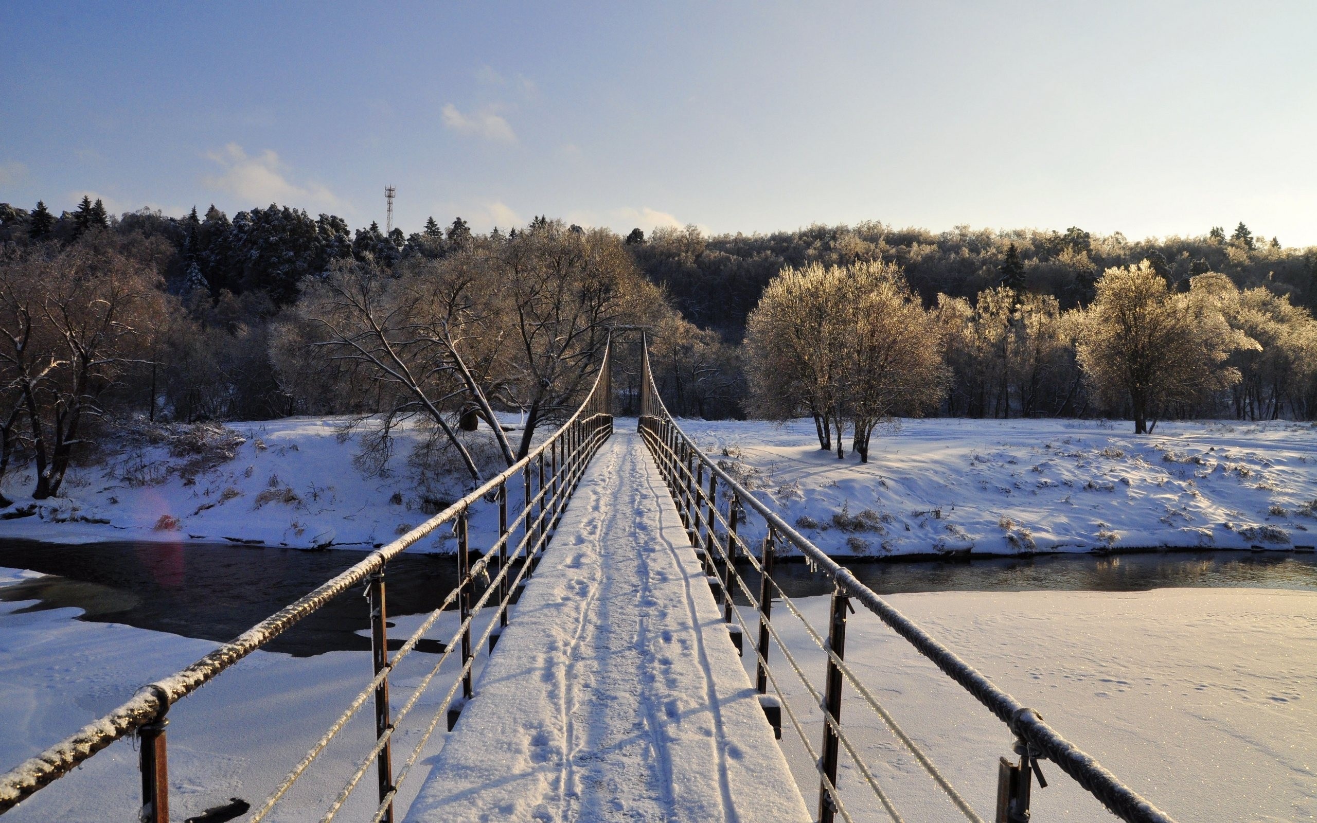 Snowy suspension bridge over a frozen river in winter HD Wallpaper