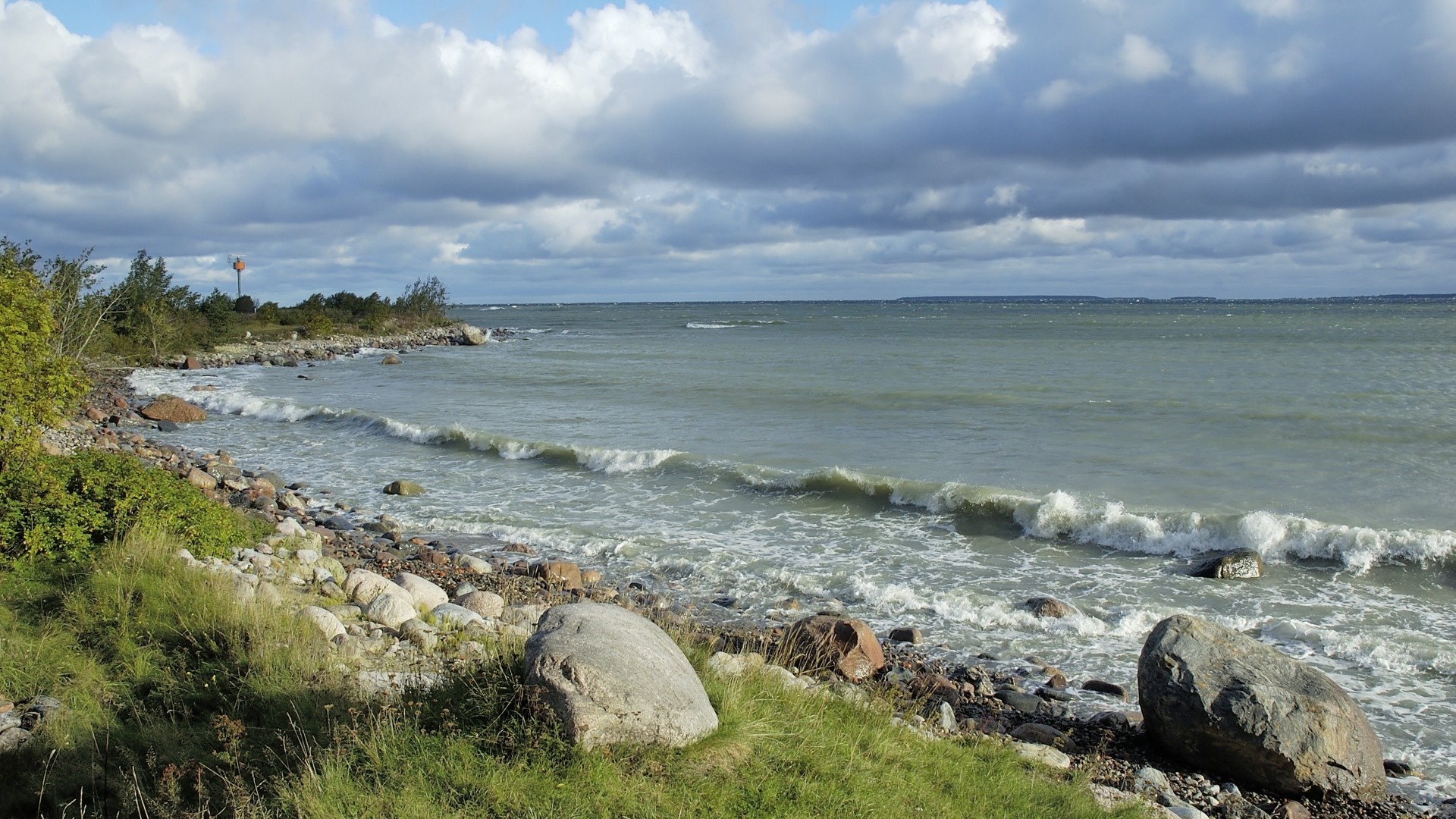 Rocky shore with waves under a cloudy sky HD Wallpaper