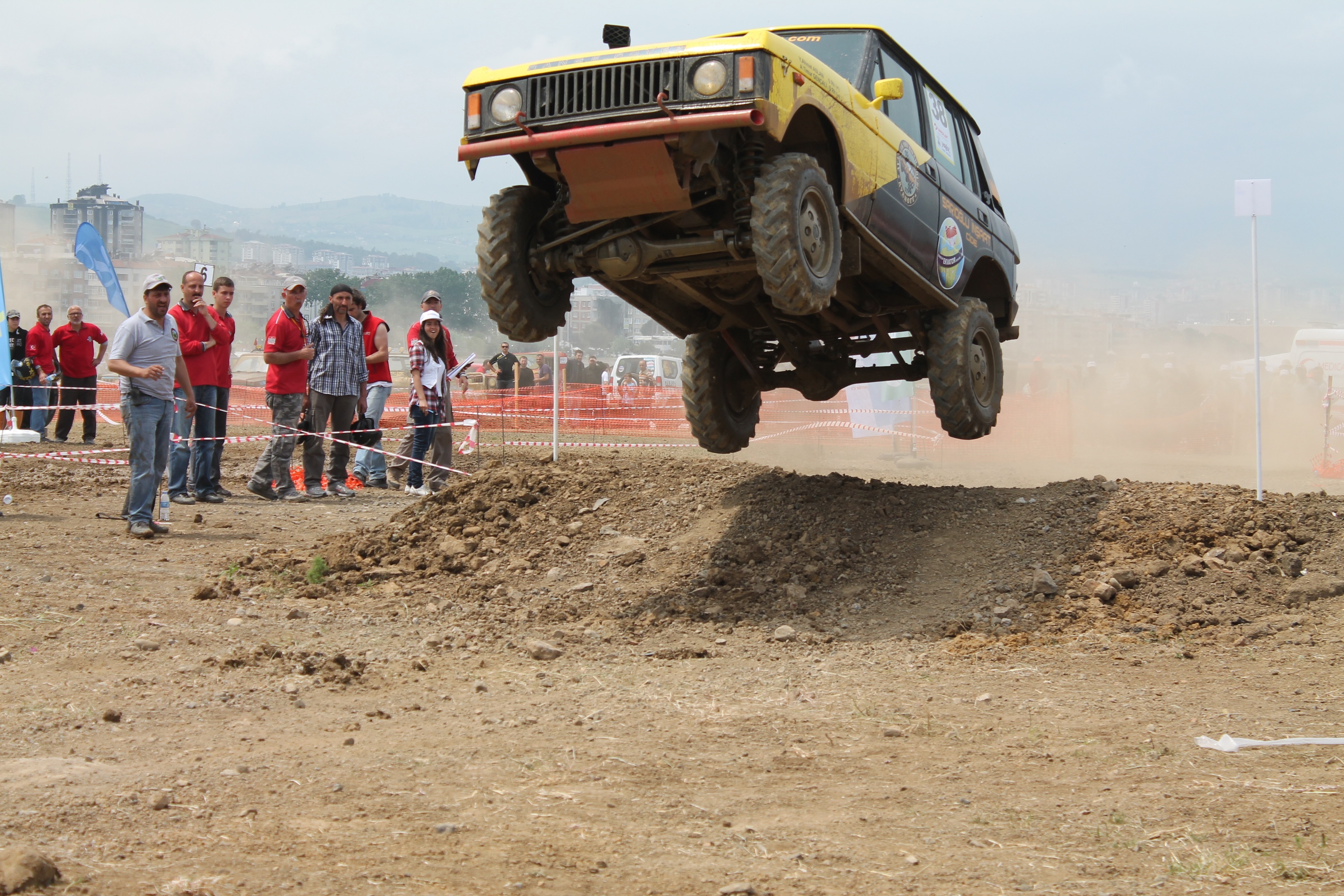 Yellow off-road vehicle jumping over dirt mound HD Wallpaper