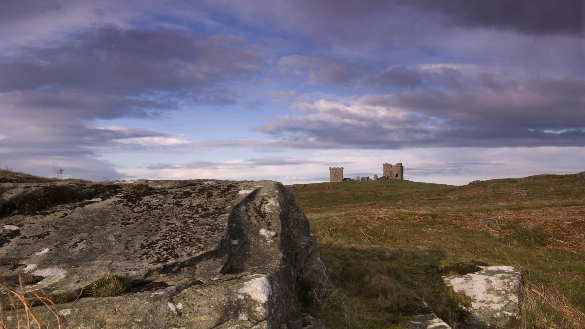 Ruined castle on a grassy hill under cloudy sky HD Wallpaper