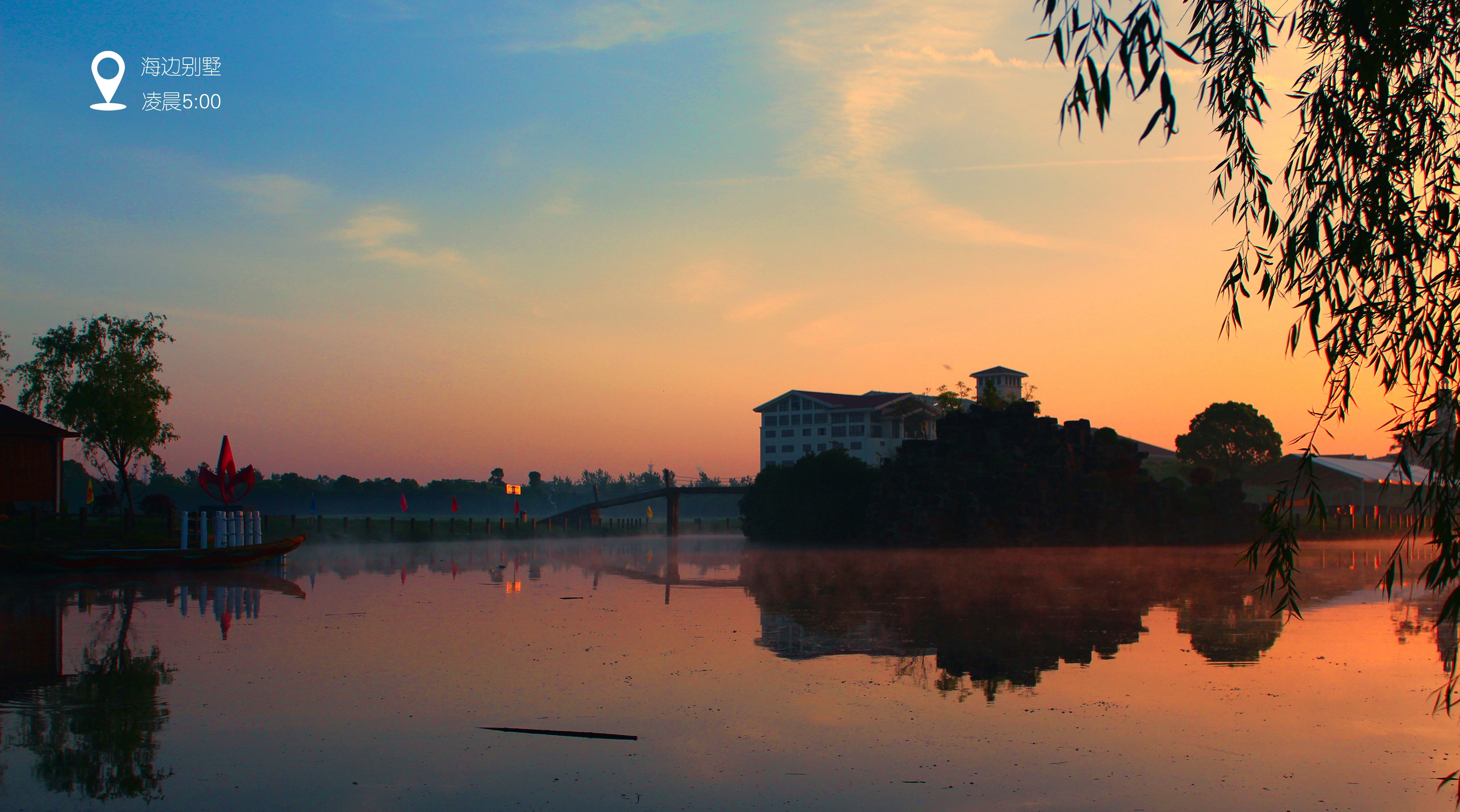 Sunrise over a calm lake with a building and trees HD Wallpaper