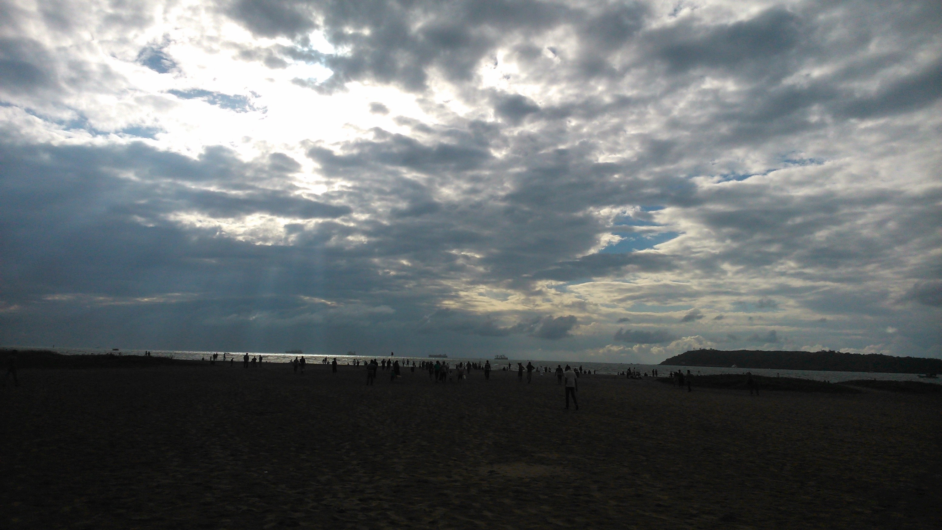 People on a beach with dramatic clouds over the sea HD Wallpaper