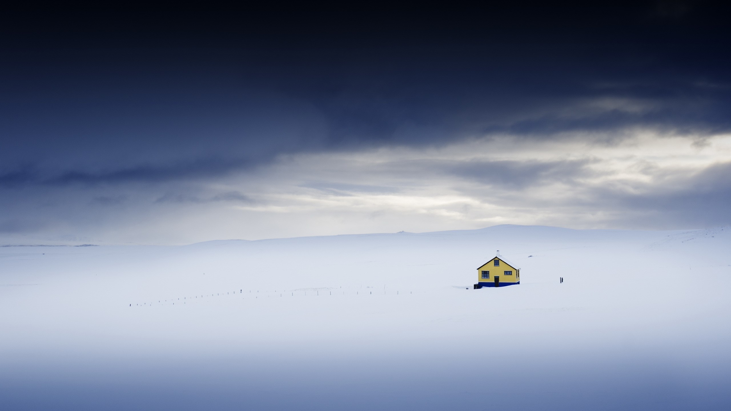 Yellow house in a vast snowy landscape under a dark sky HD Wallpaper