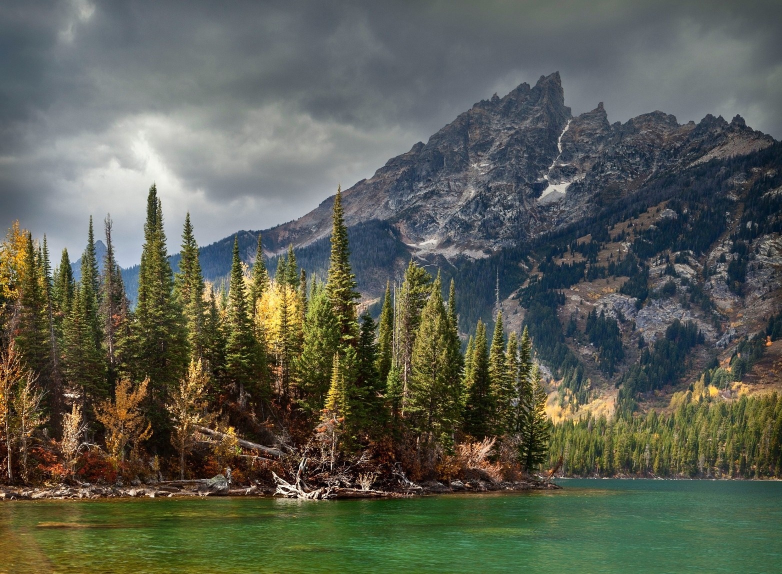 Lake and mountains with pine trees under stormy clouds HD Wallpaper