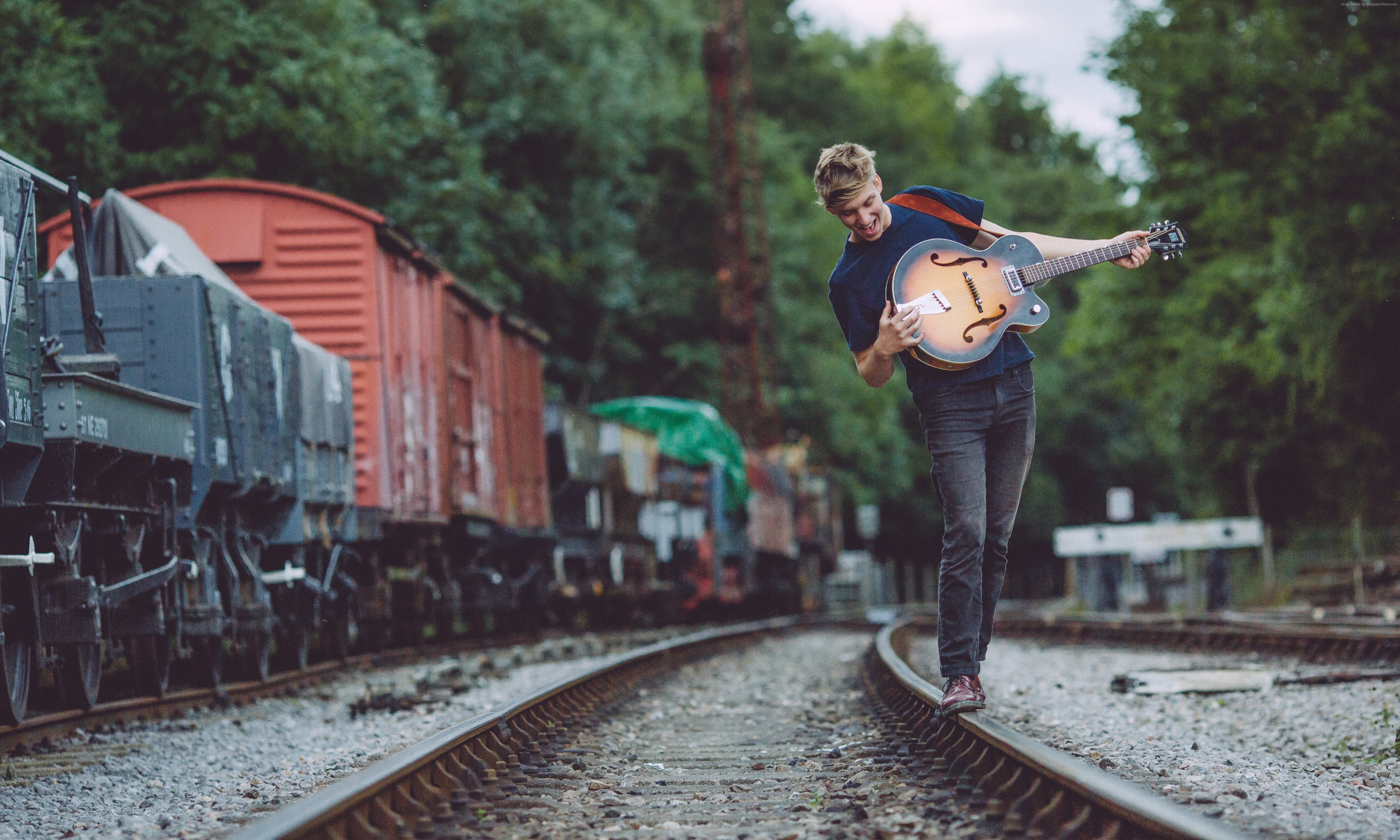 George Ezra on train tracks with guitar HD Wallpaper