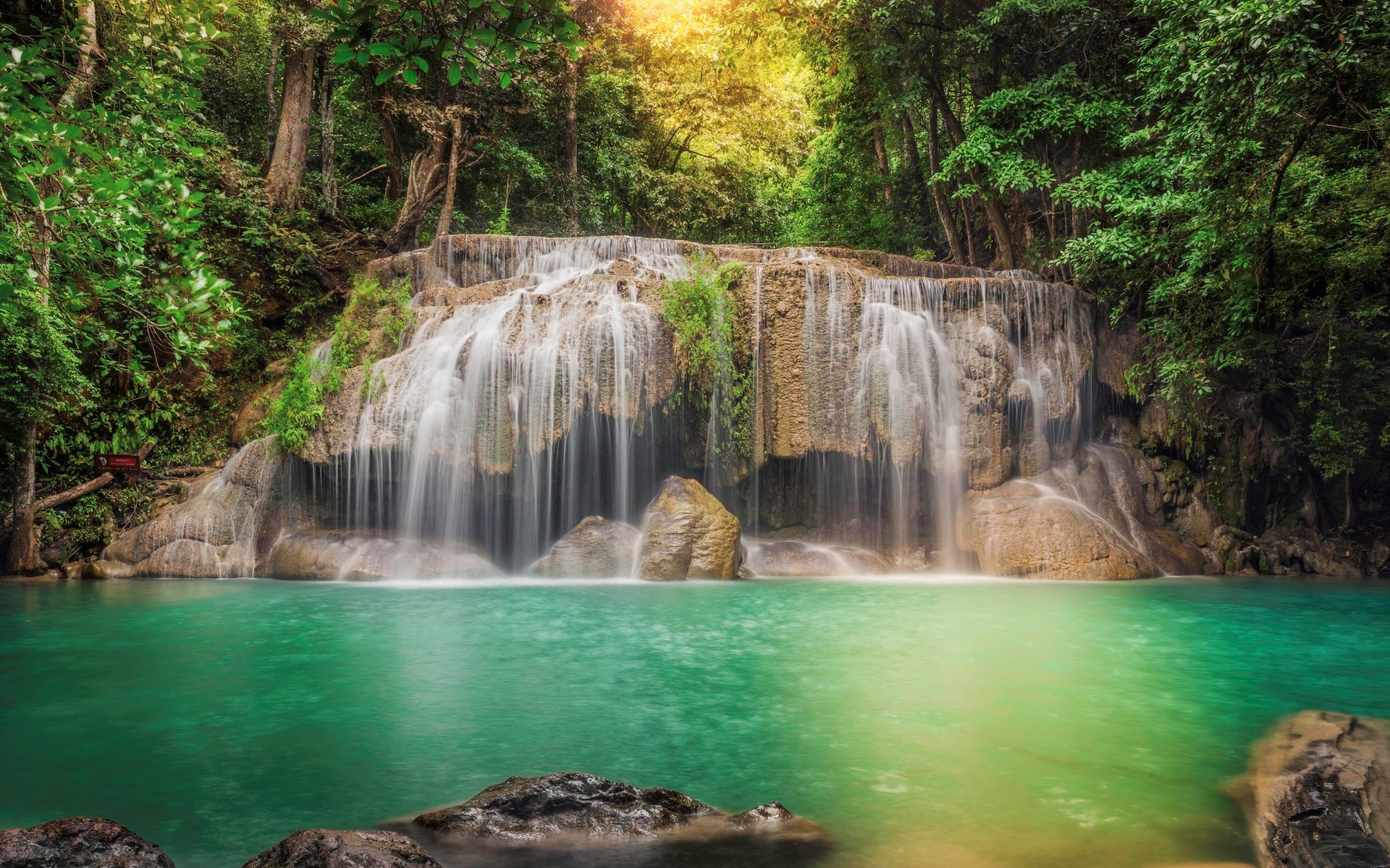 Waterfall cascading into a turquoise pool in a lush forest HD Wallpaper