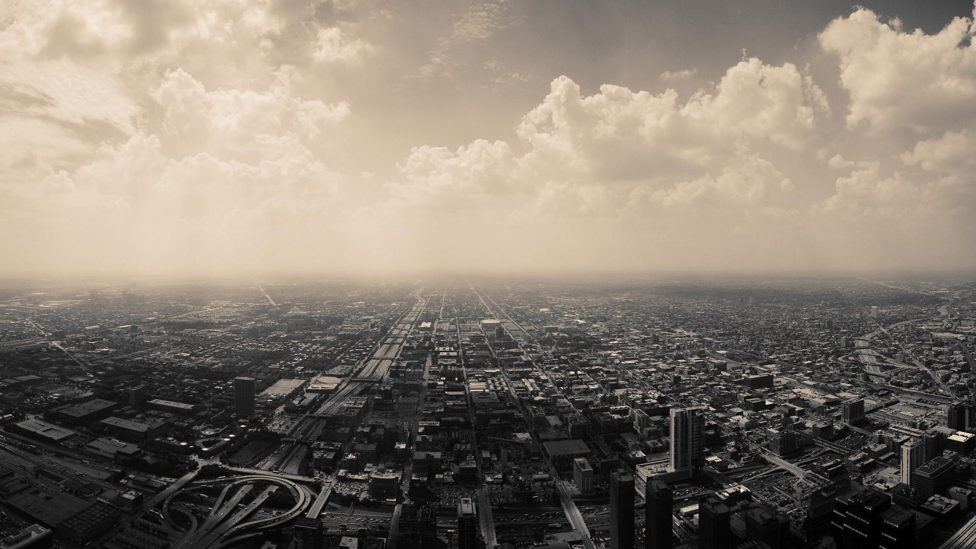 Aerial view of a sprawling city under a cloudy sky HD Wallpaper