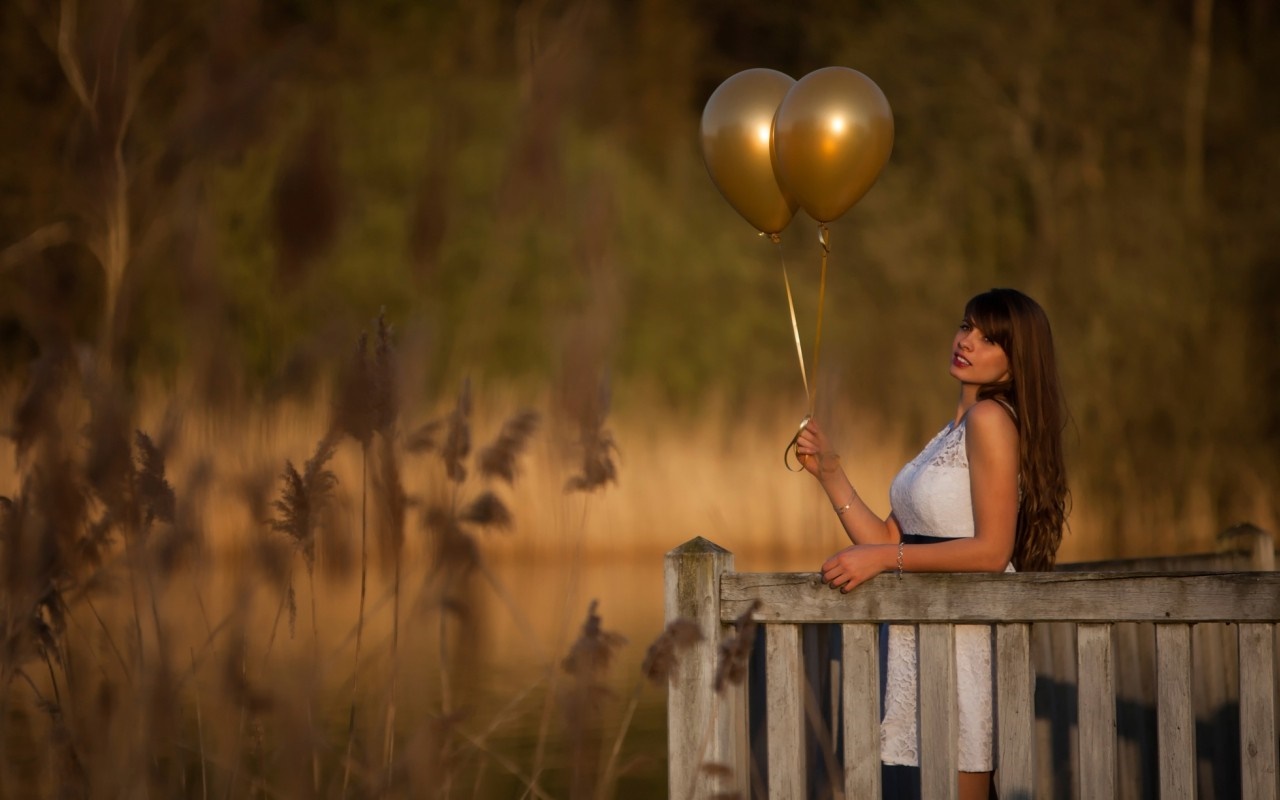 Woman holding golden balloons on a wooden deck HD Wallpaper