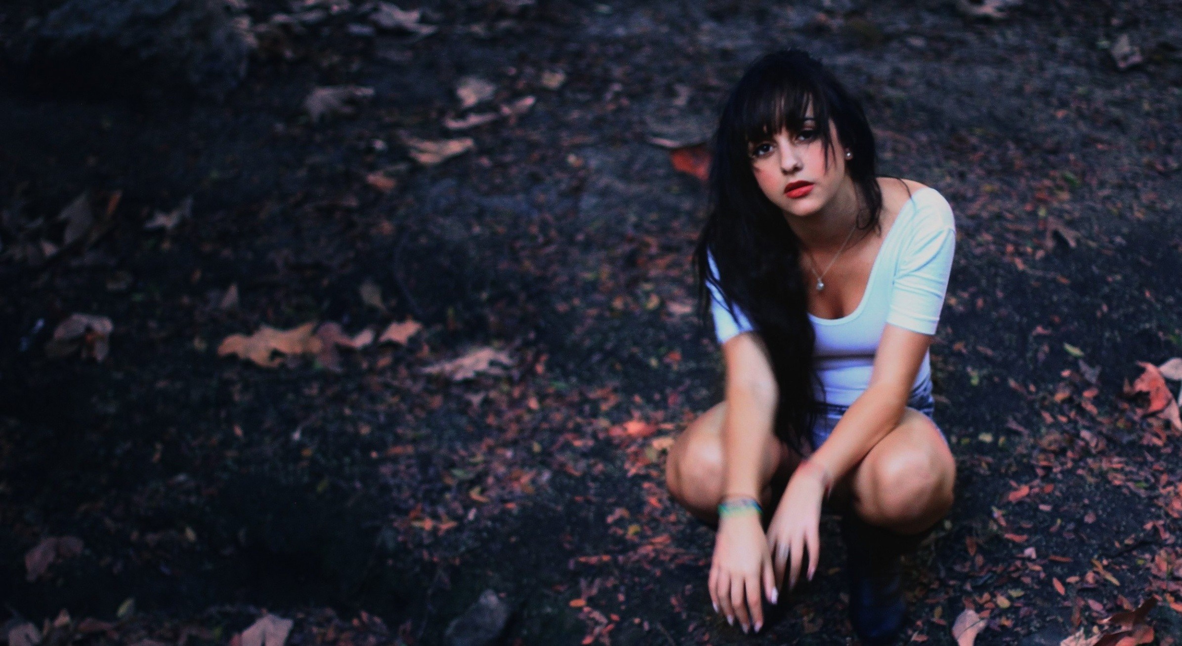 Woman with long dark hair crouching outdoors HD Wallpaper