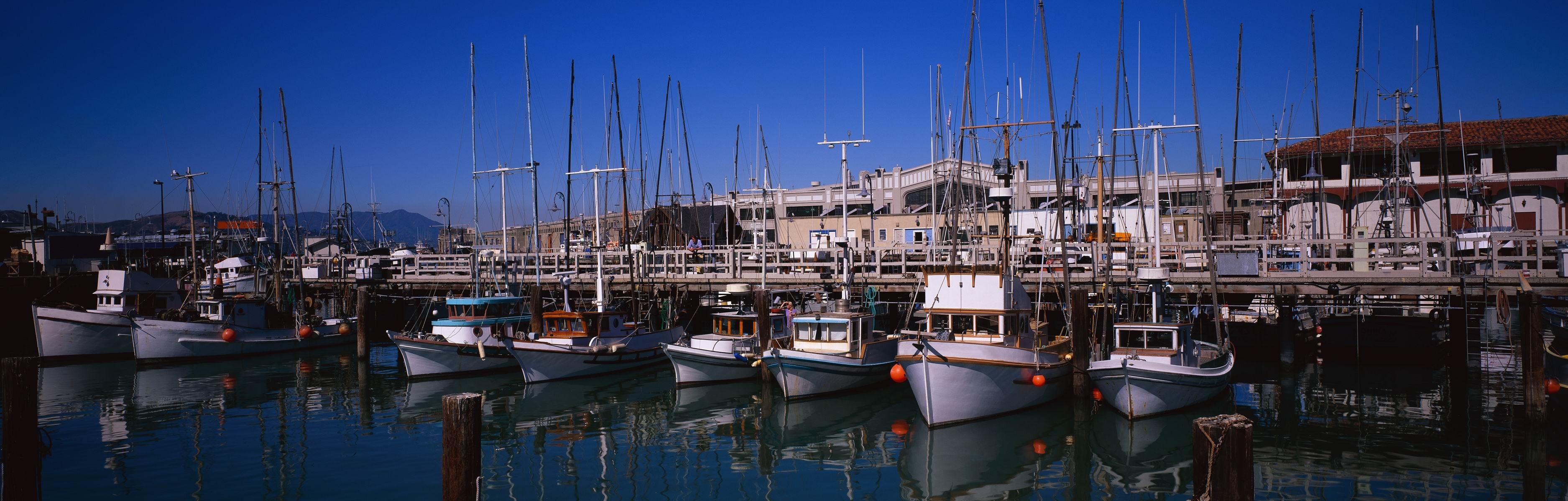 Boats docked at a pier with buildings in the background HD Wallpaper