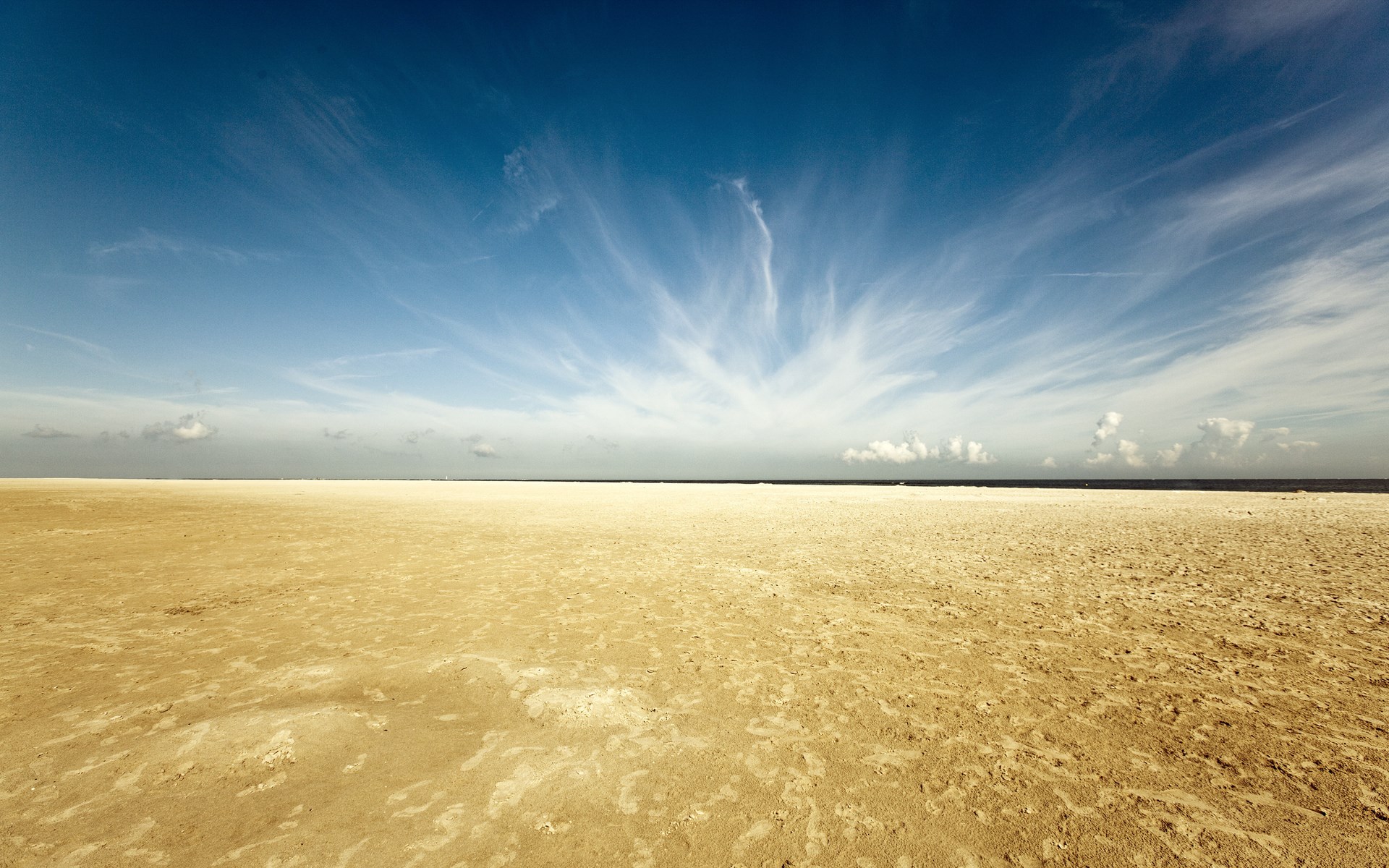 Vast sandy beach under a wide blue sky with wispy clouds HD Wallpaper