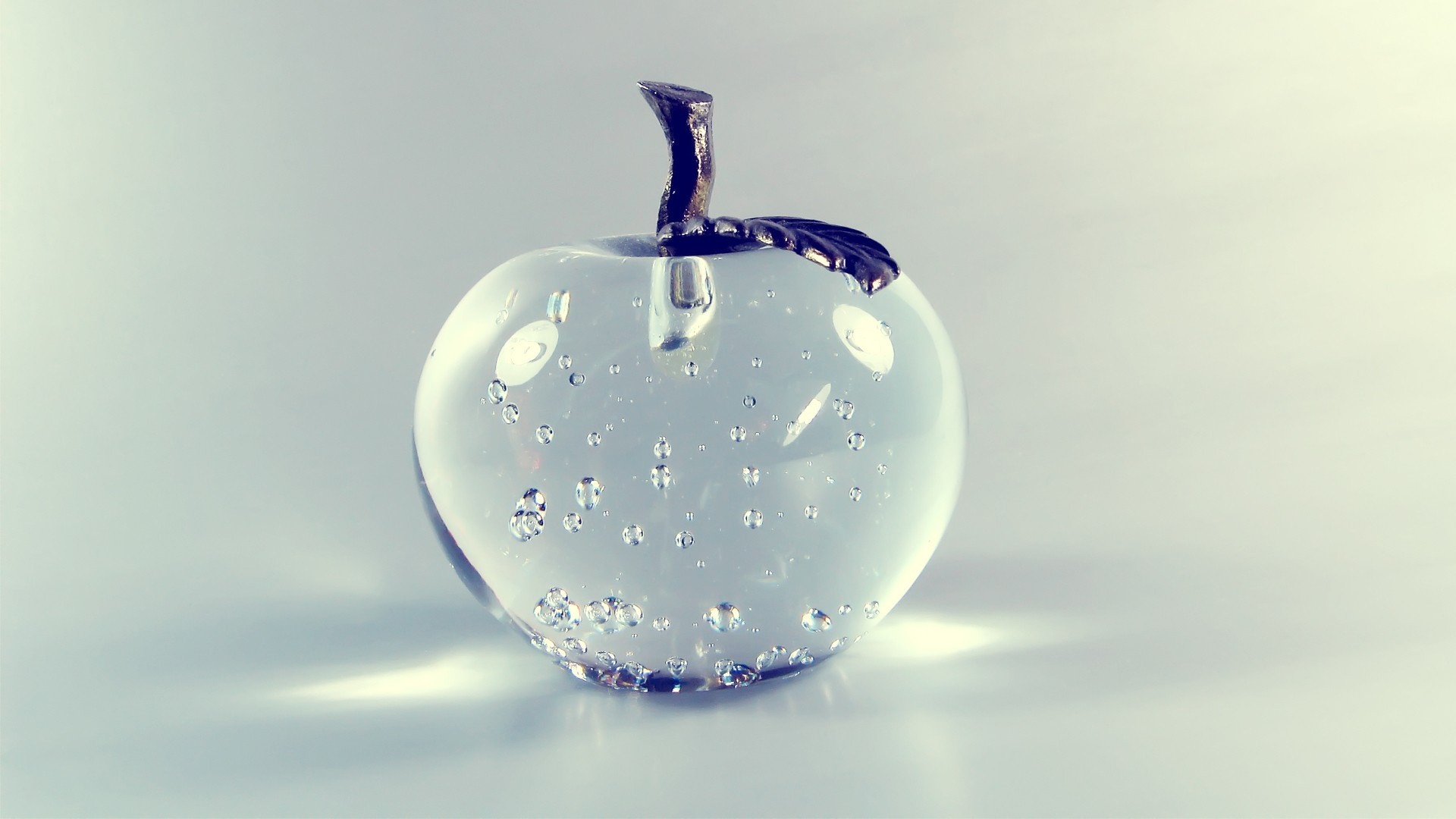 Glass apple with bubbles and metal stem HD Wallpaper