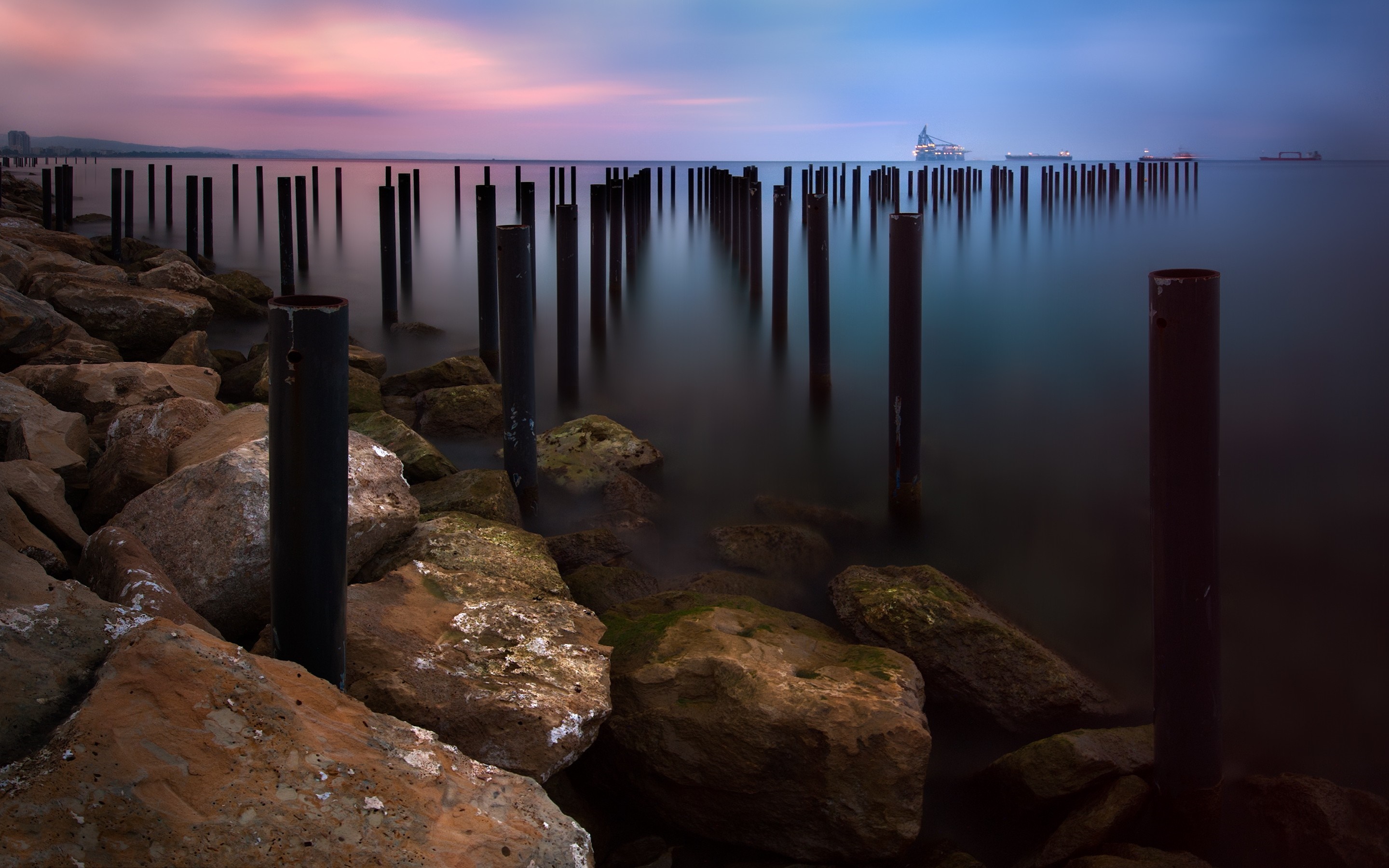 Long exposure of sea with pillars and ships at sunset HD Wallpaper