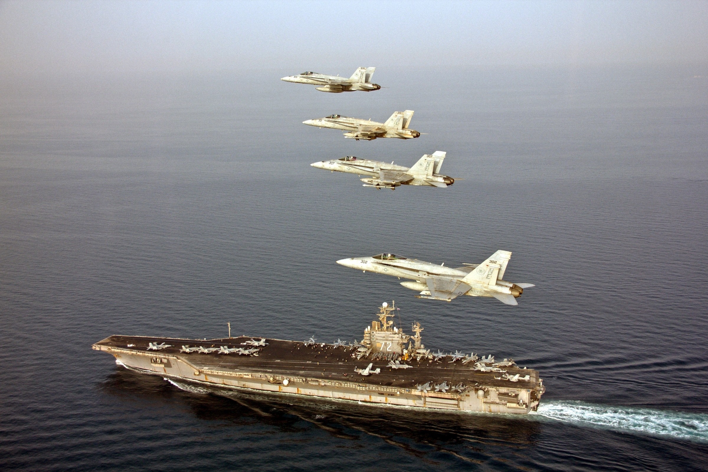 Aircraft carrier with F/A-18 Hornets flying in formation HD Wallpaper