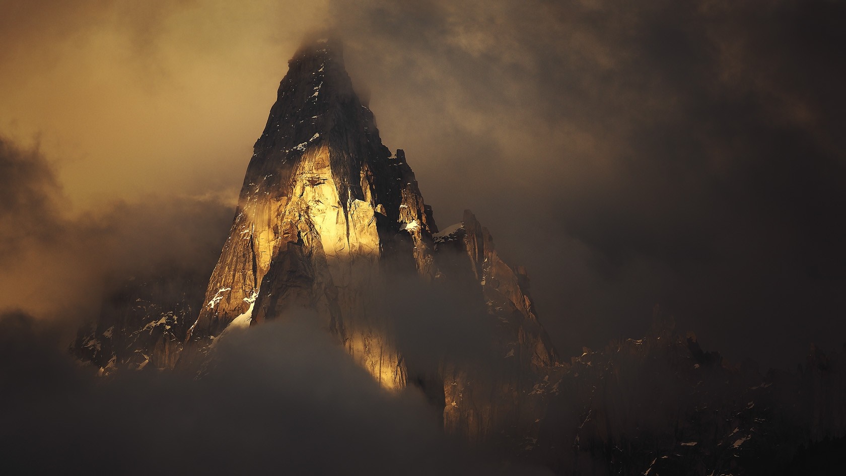 Mountain peak illuminated by sunlight through clouds HD Wallpaper