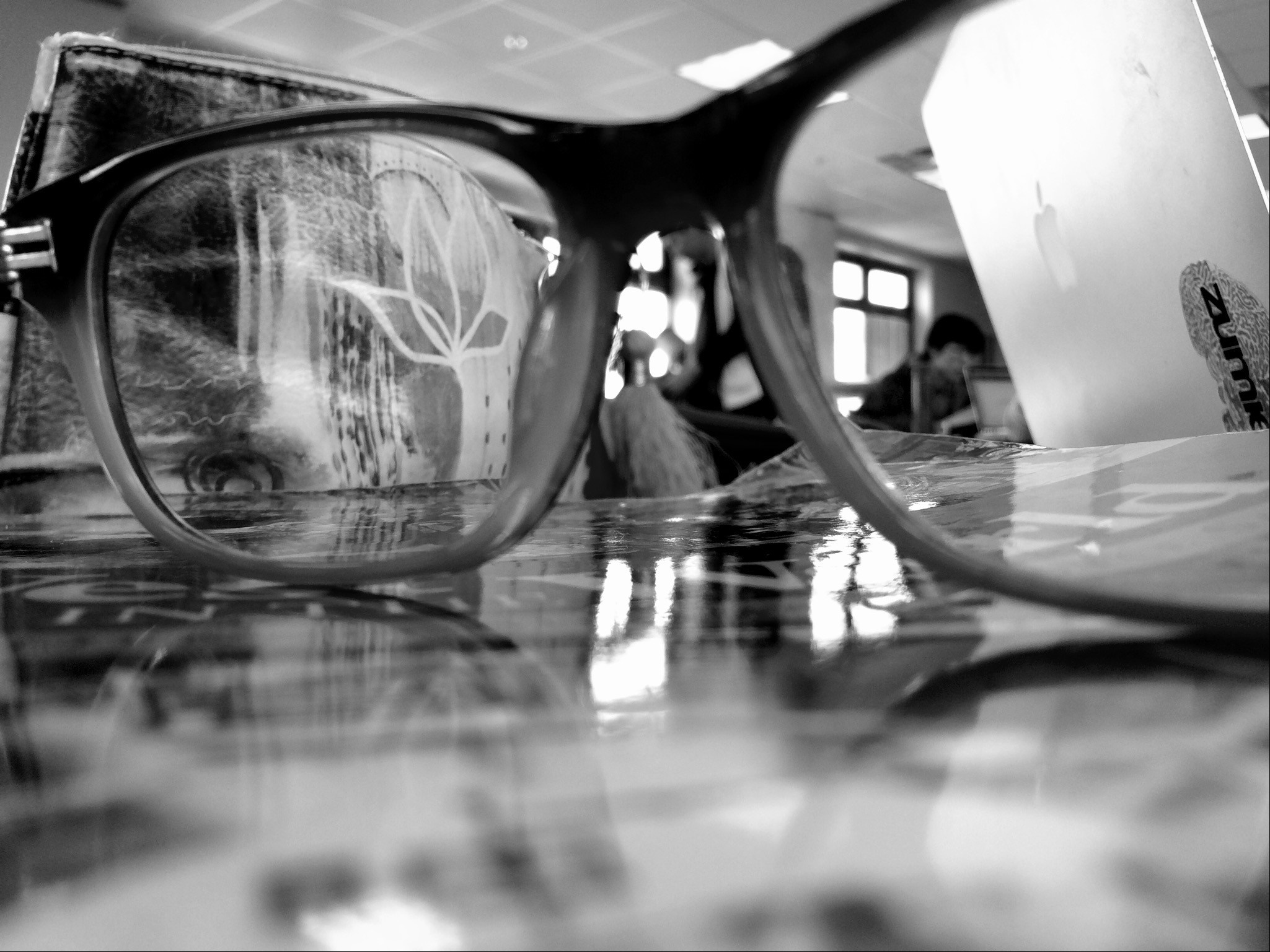 Black and white close-up of eyeglasses on a table HD Wallpaper