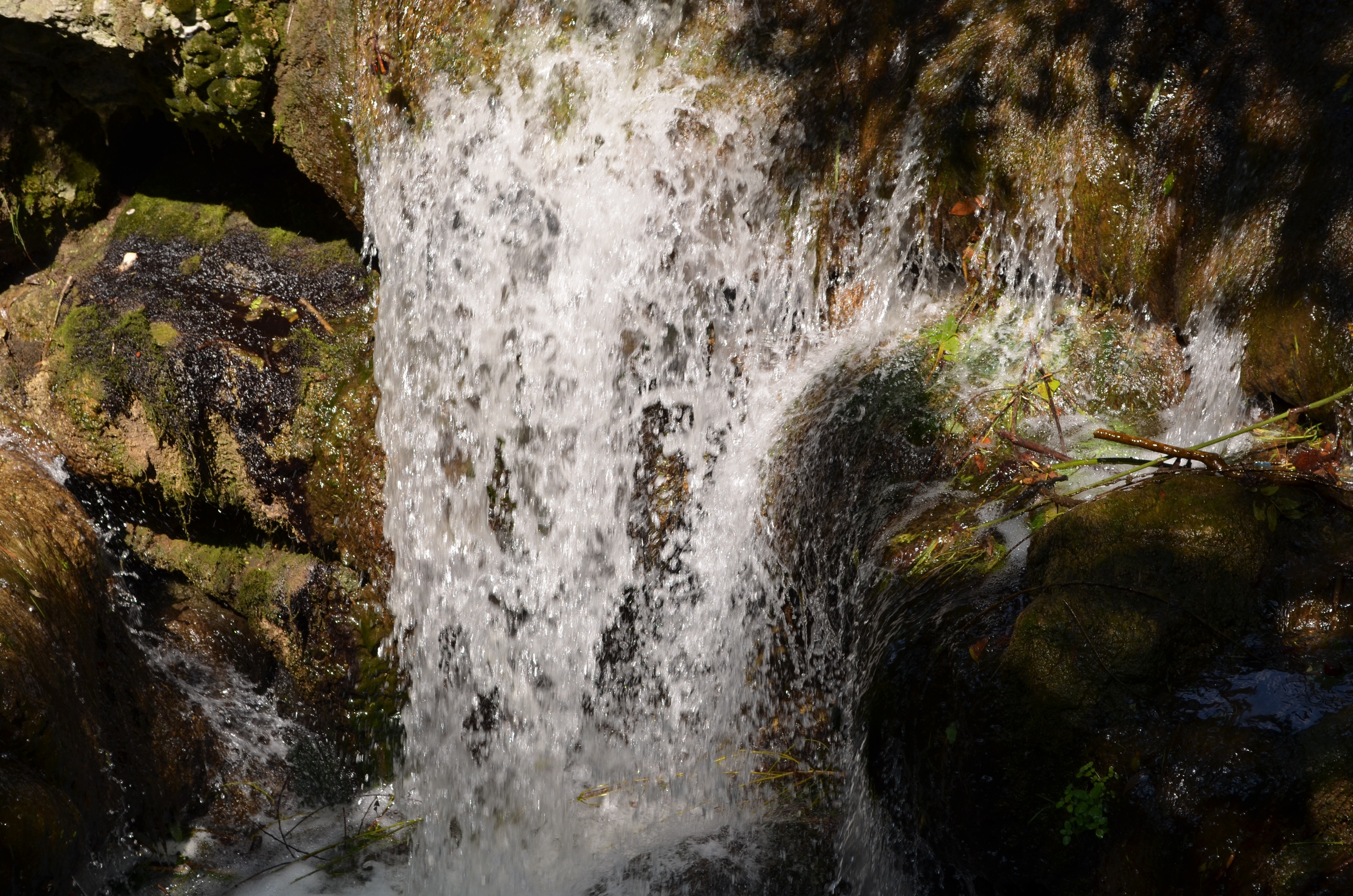 Waterfall cascading over mossy rocks in a forest HD Wallpaper