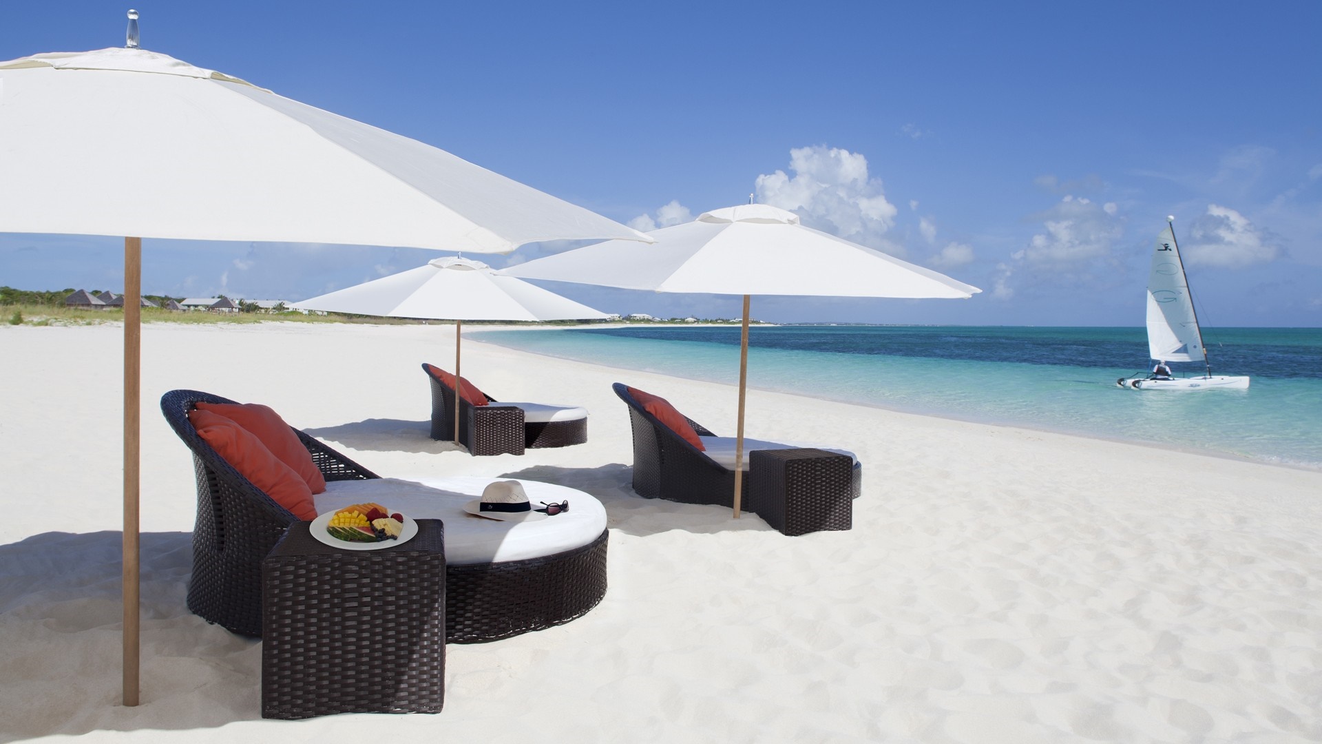 Tropical beach with lounge chairs, umbrellas, and sailboat HD Wallpaper