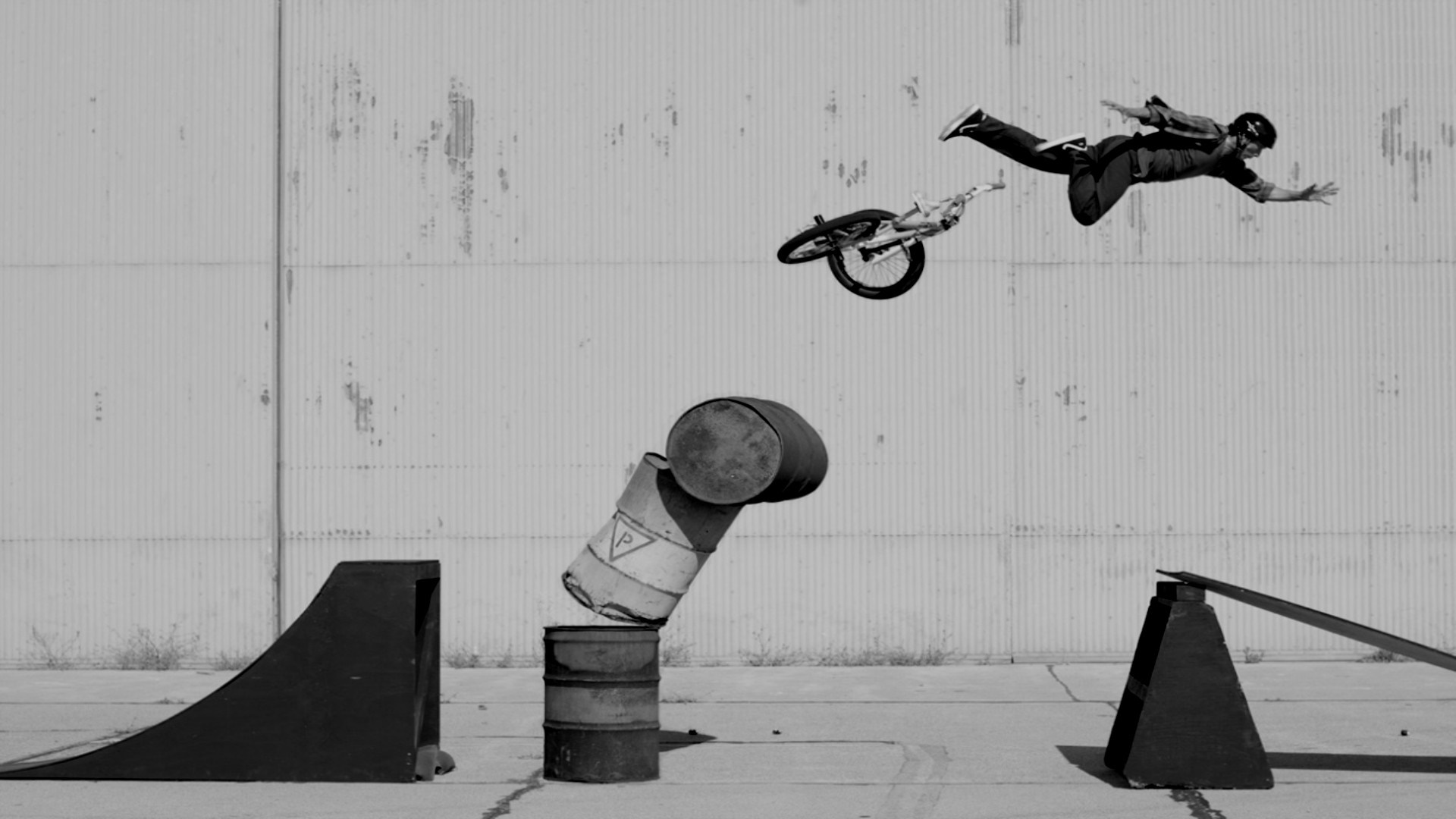 BMX rider performing a trick over barrels HD Wallpaper