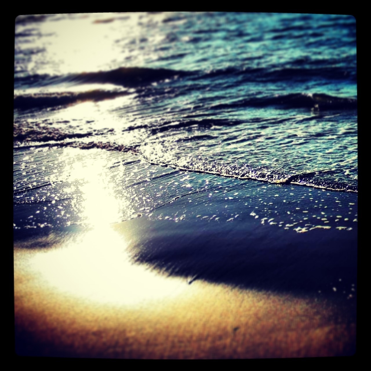 Sunlight reflecting on the ocean waves at sunset on a beach HD Wallpaper