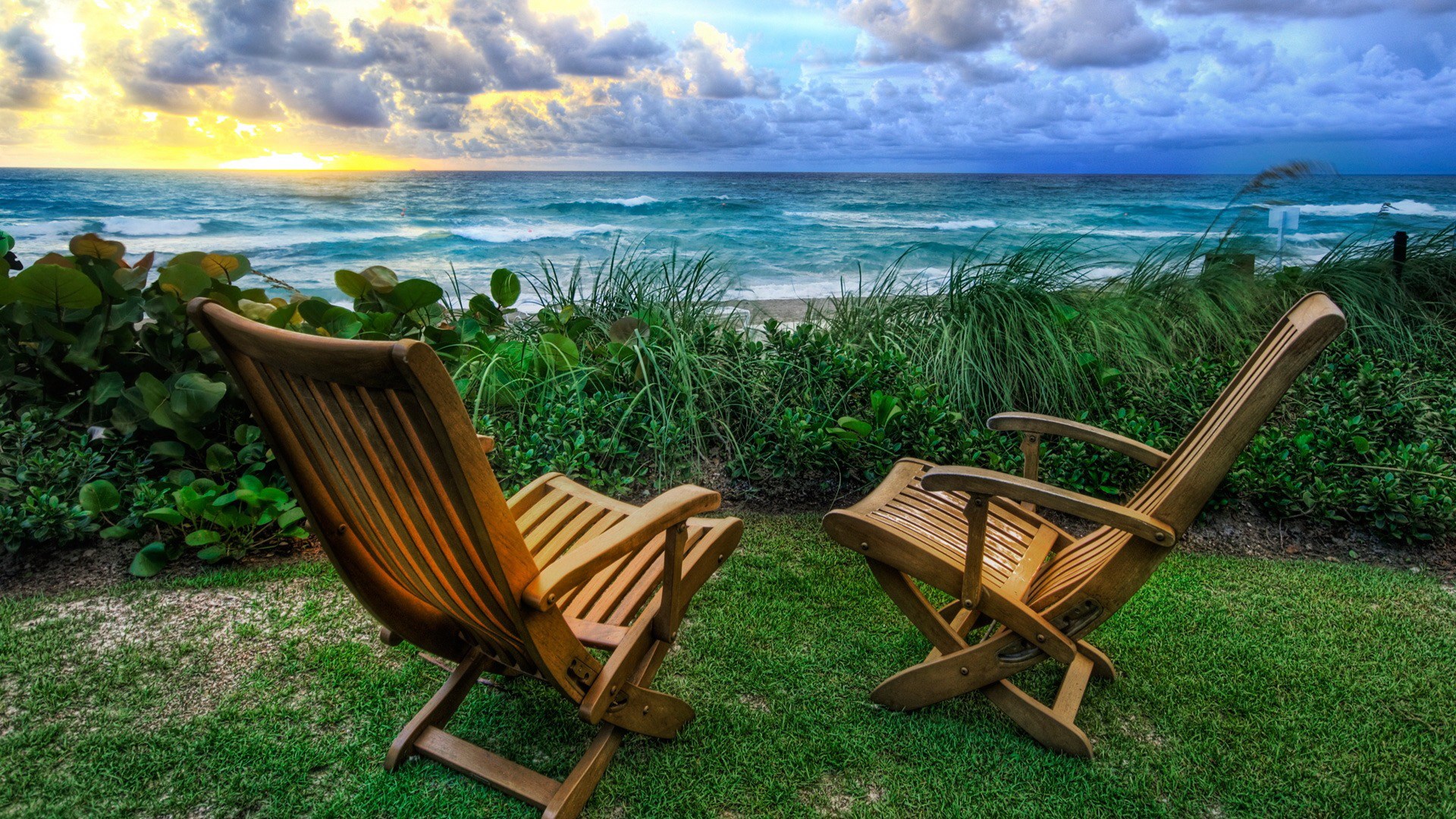 Two wooden chairs on a lawn overlooking the ocean HD Wallpaper