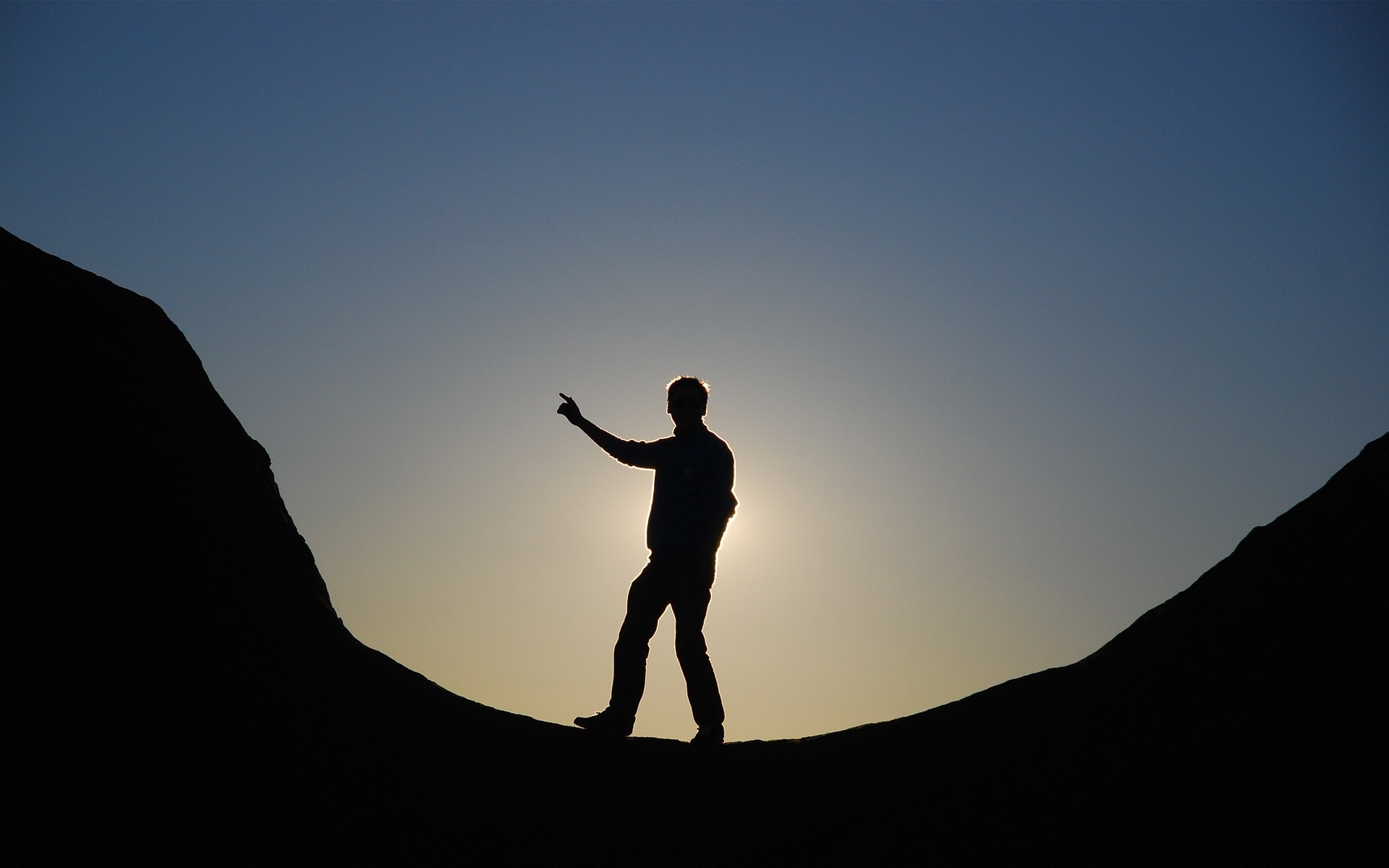 Silhouette of a man pointing at the sunset between mountains HD Wallpaper