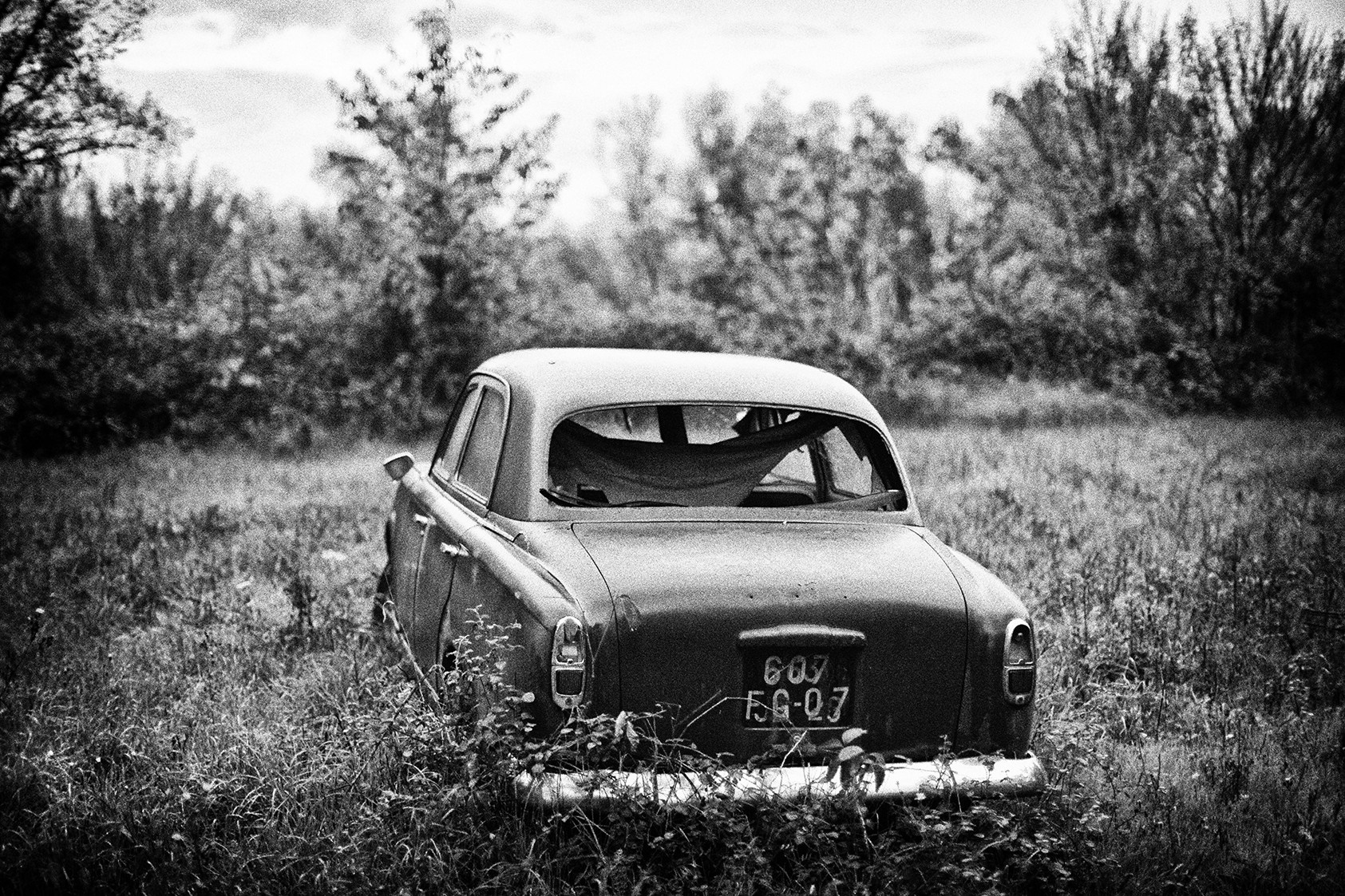 Abandoned vintage car in a grassy field HD Wallpaper