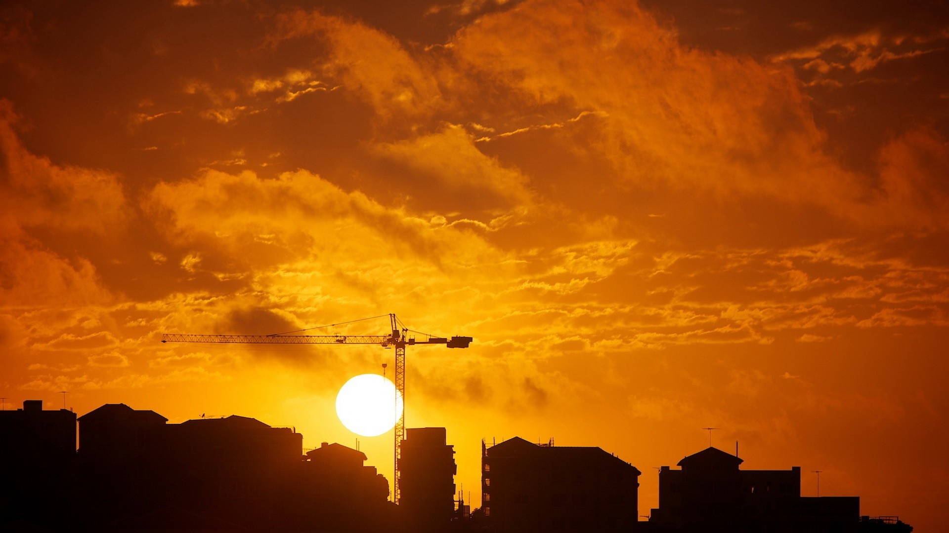 Sunset over cityscape with construction crane HD Wallpaper