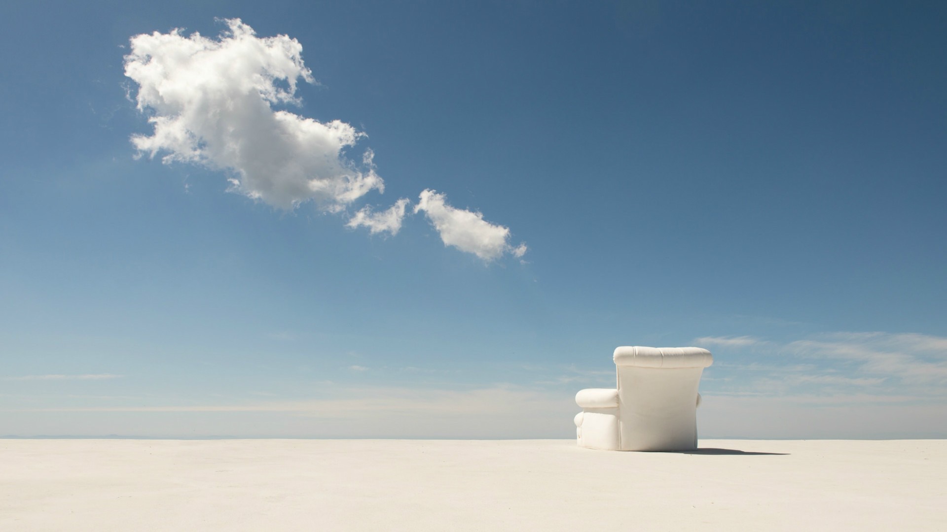 White armchair on a vast white plain under a blue sky with clouds HD Wallpaper