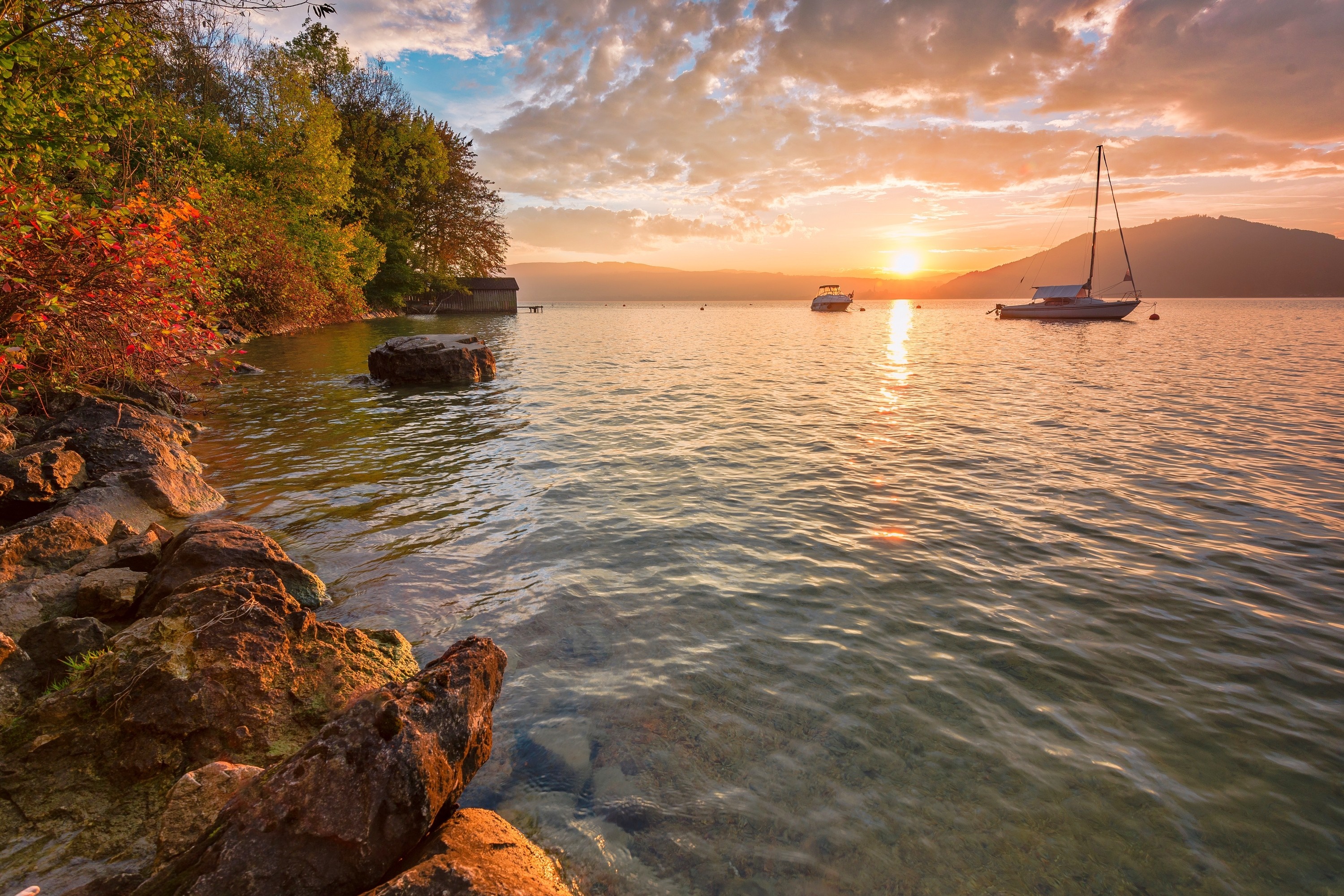 Sailboat and boat on a lake at sunset with trees on shore HD Wallpaper