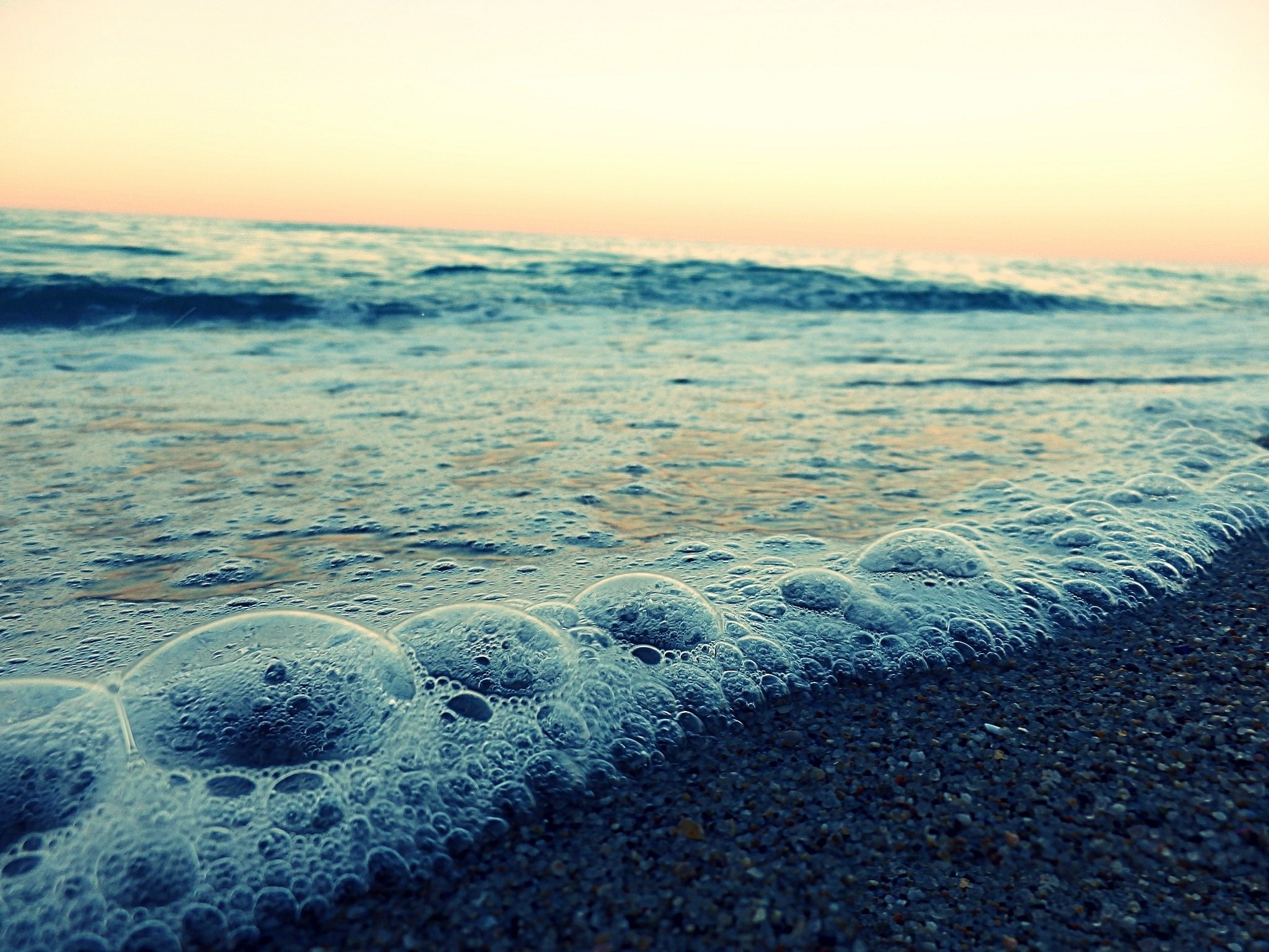 Ocean waves with bubbles on the shore at sunset HD Wallpaper
