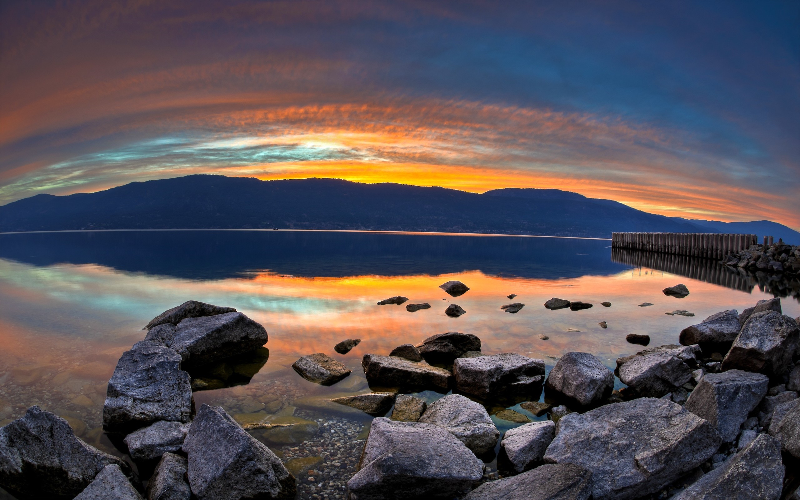 Sunset over a calm lake with mountains and rocks HD Wallpaper